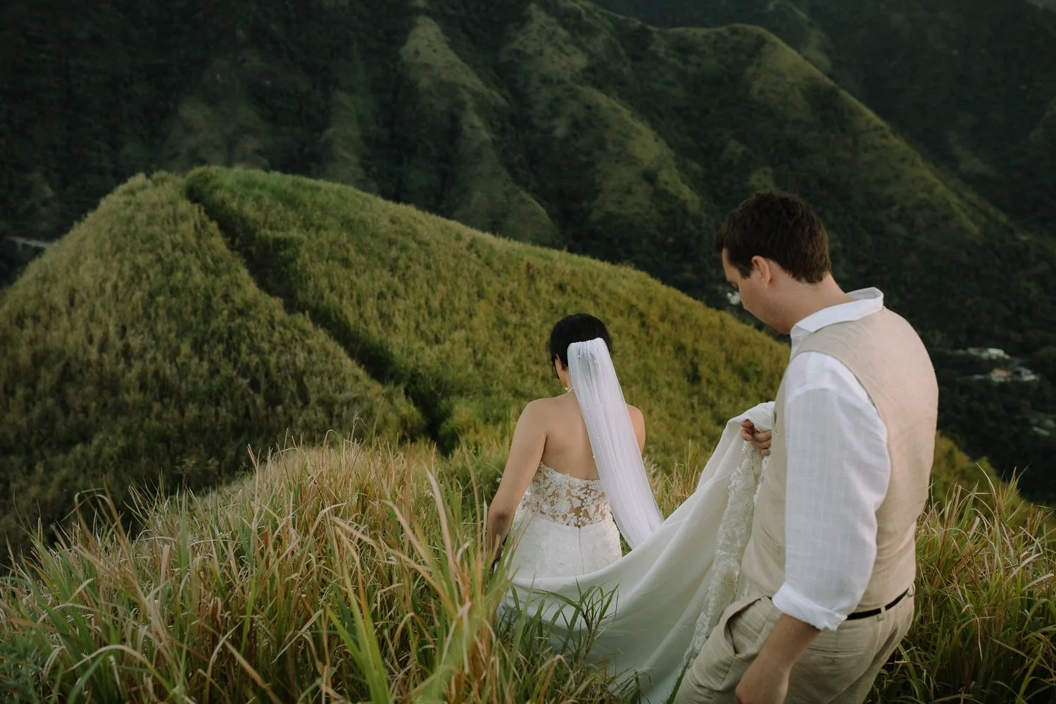 Bride and groom walking down a grassy mountain ridge after their elopement photo session