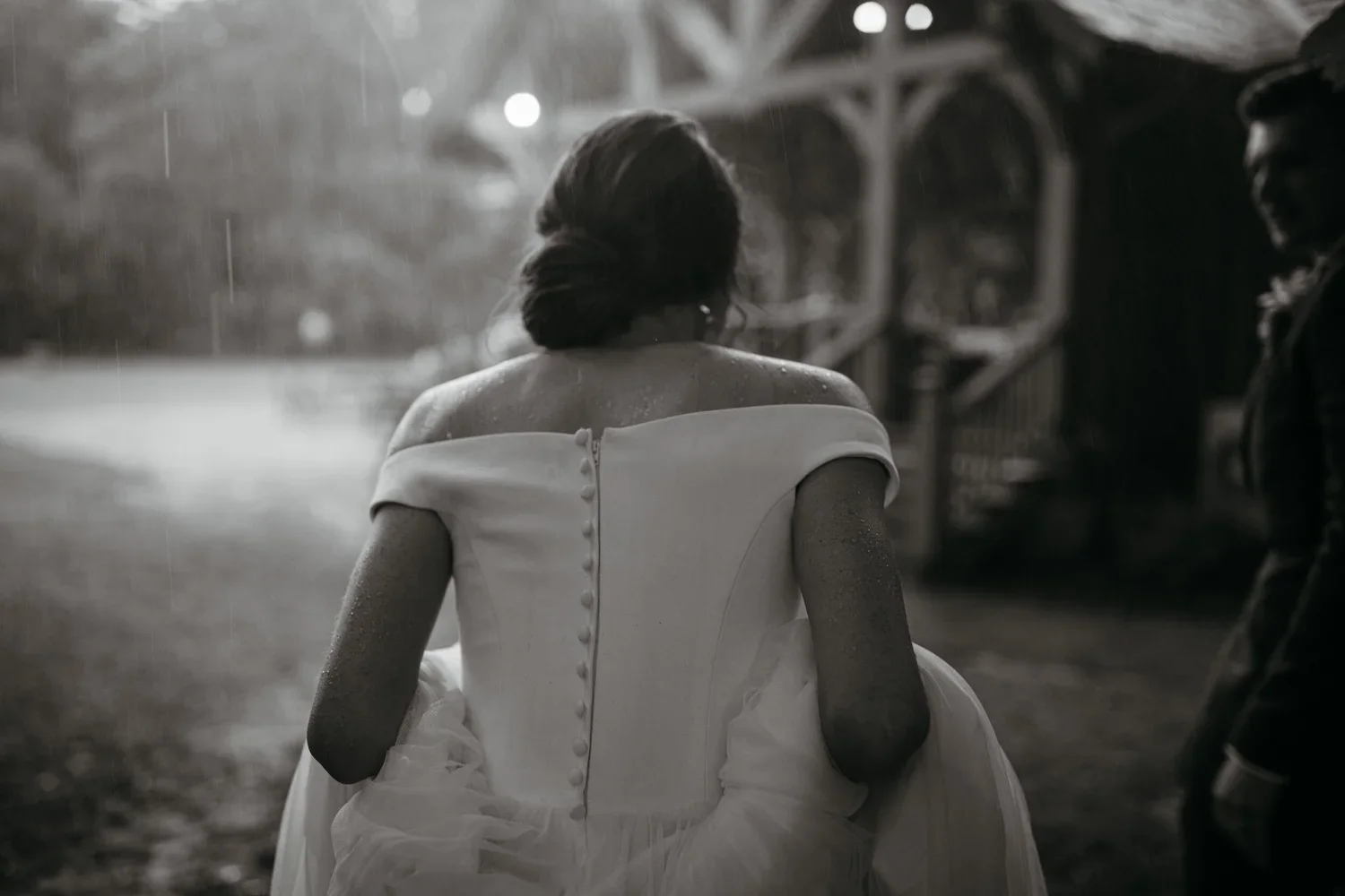 Black and white photo of bride in rain on wedding day, real emotional moment
