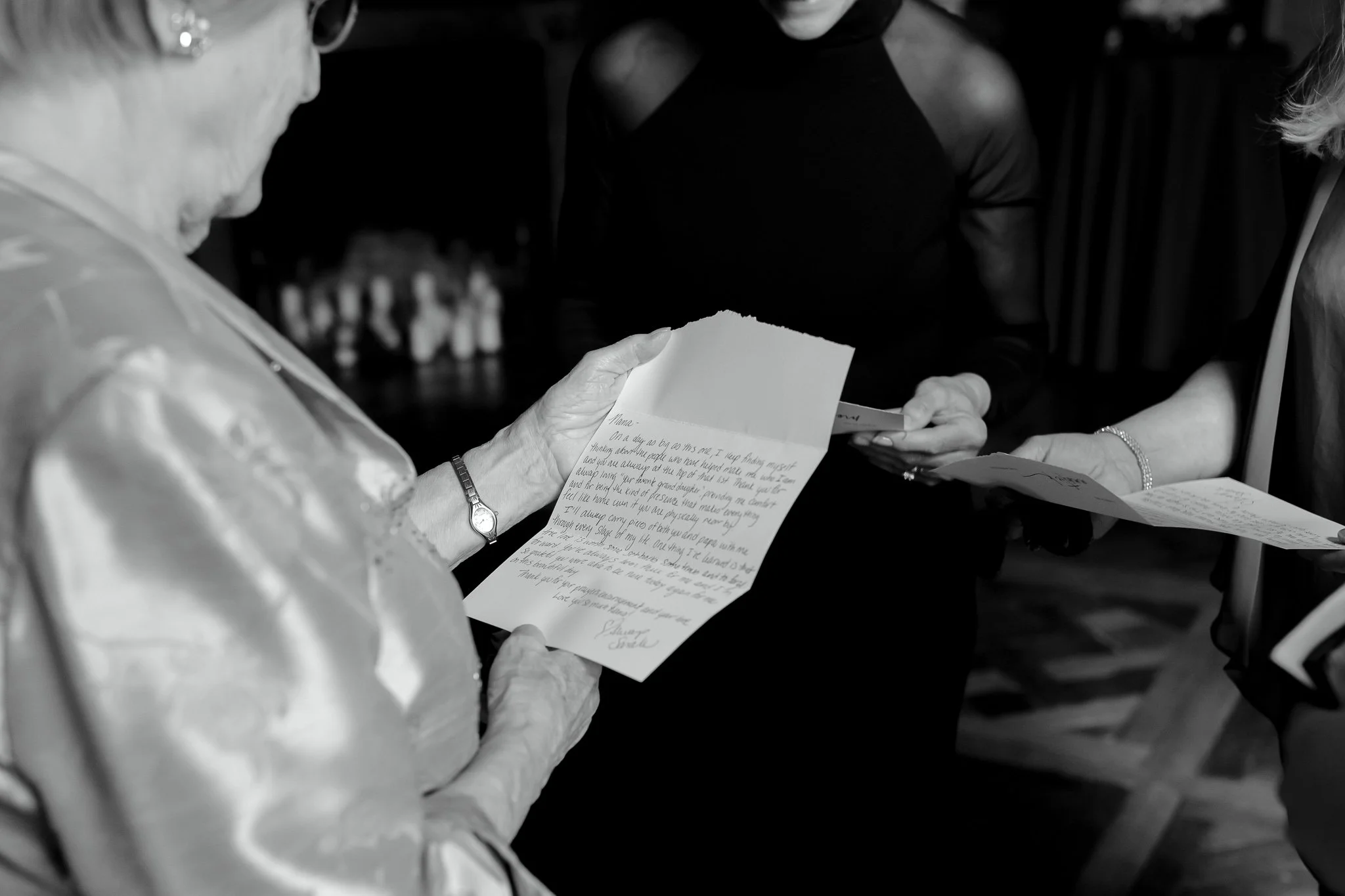 Black and white image of family reading handwritten letters during wedding morning