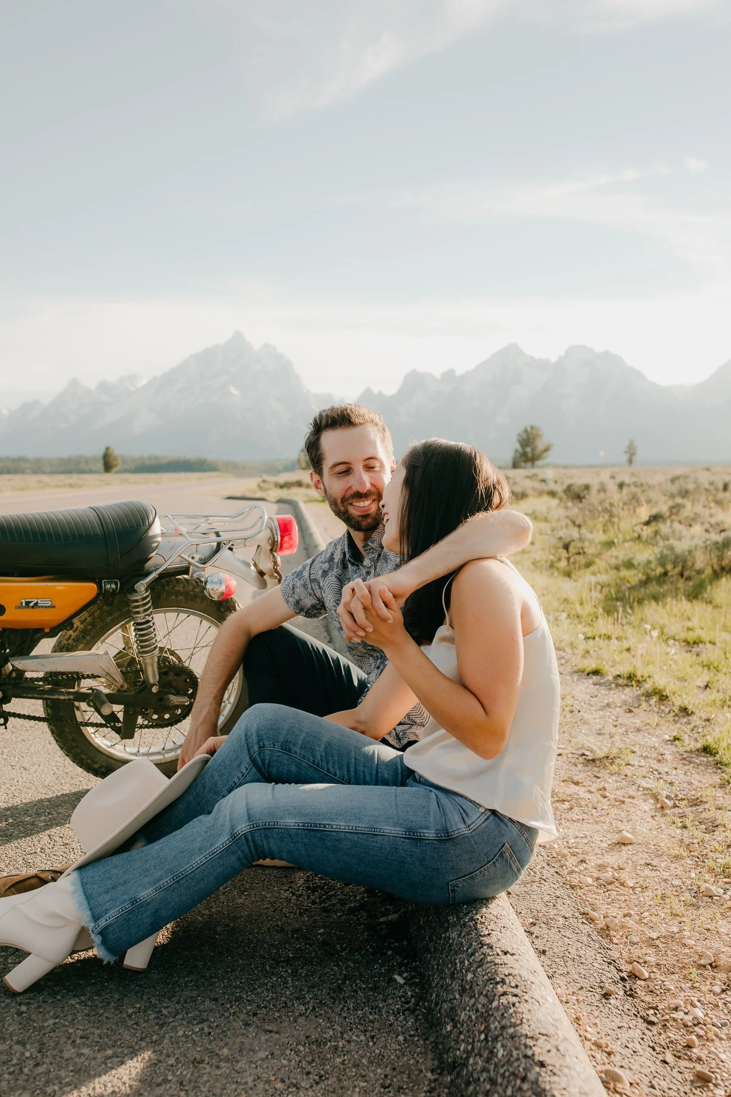 Wide view of couple seated beside a motorcycle during a Jackson Hole engagement session