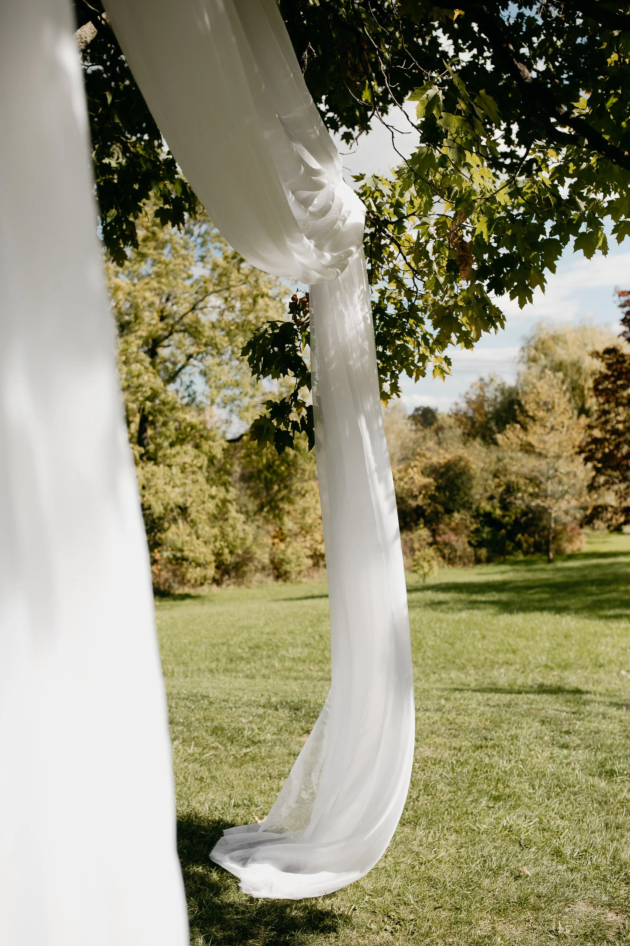 Soft white fabric draped from the branches of an oak tree during an outdoor wedding ceremony at Windrift Hall in the Hudson Valley