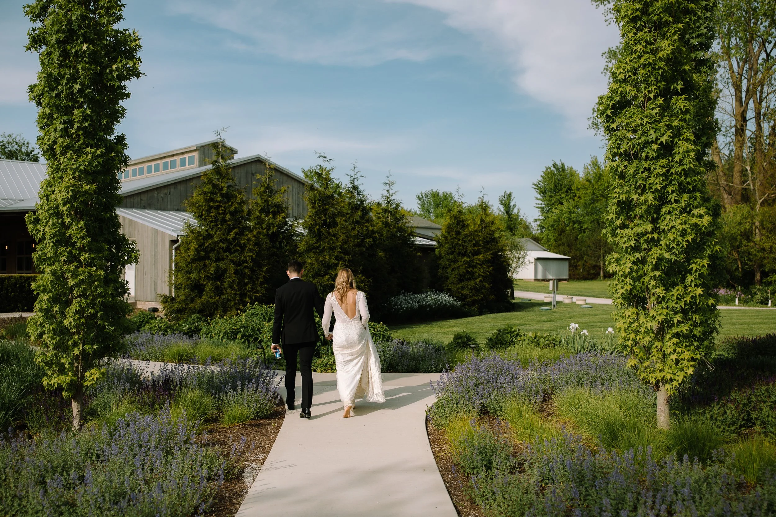 Bride and groom walking along a garden path at Jorgensen Farm The Gardens in Columbus, Ohio.