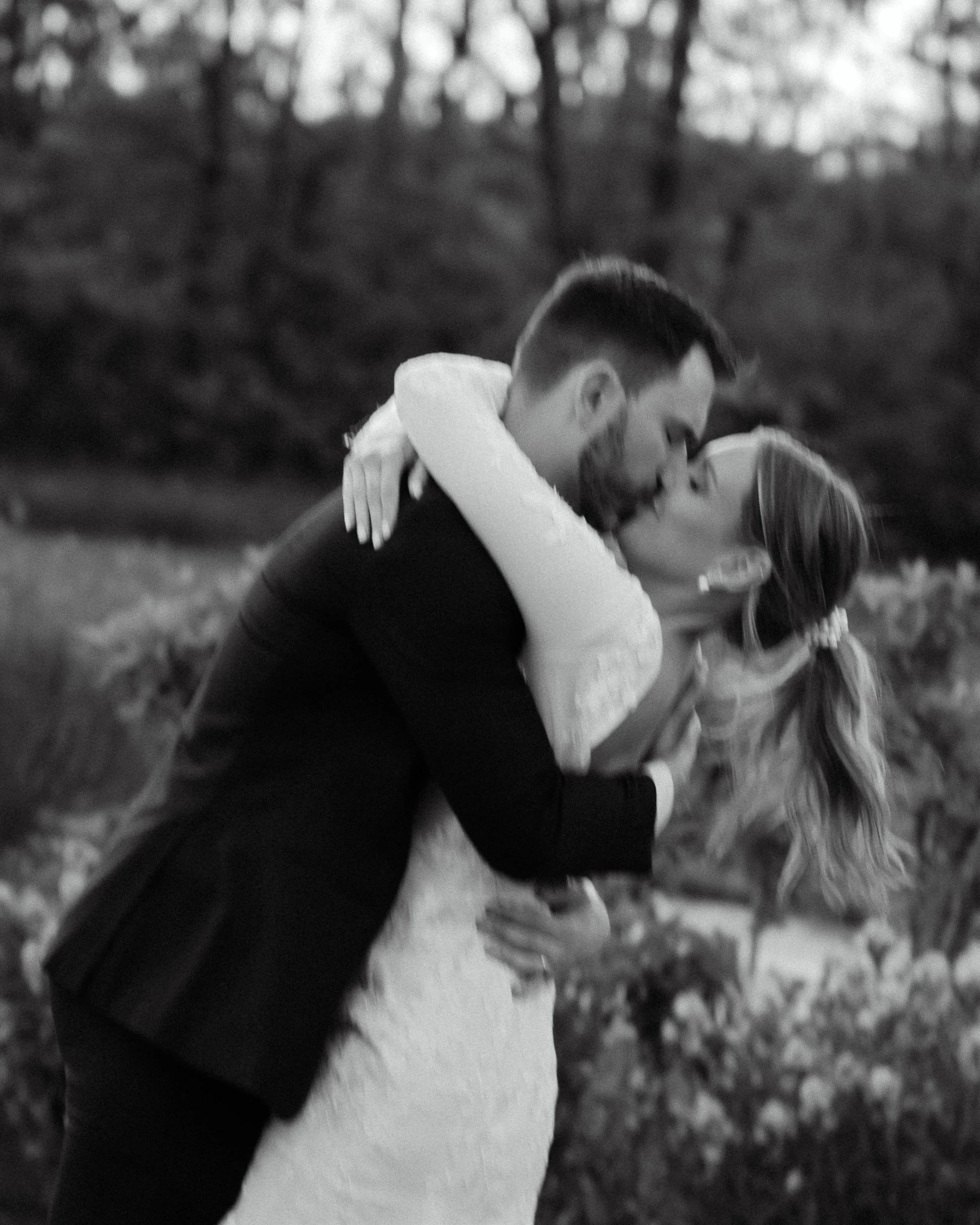 Black and white portrait of the bride and groom kissing in the gardens at Jorgensen Farm The Gardens.