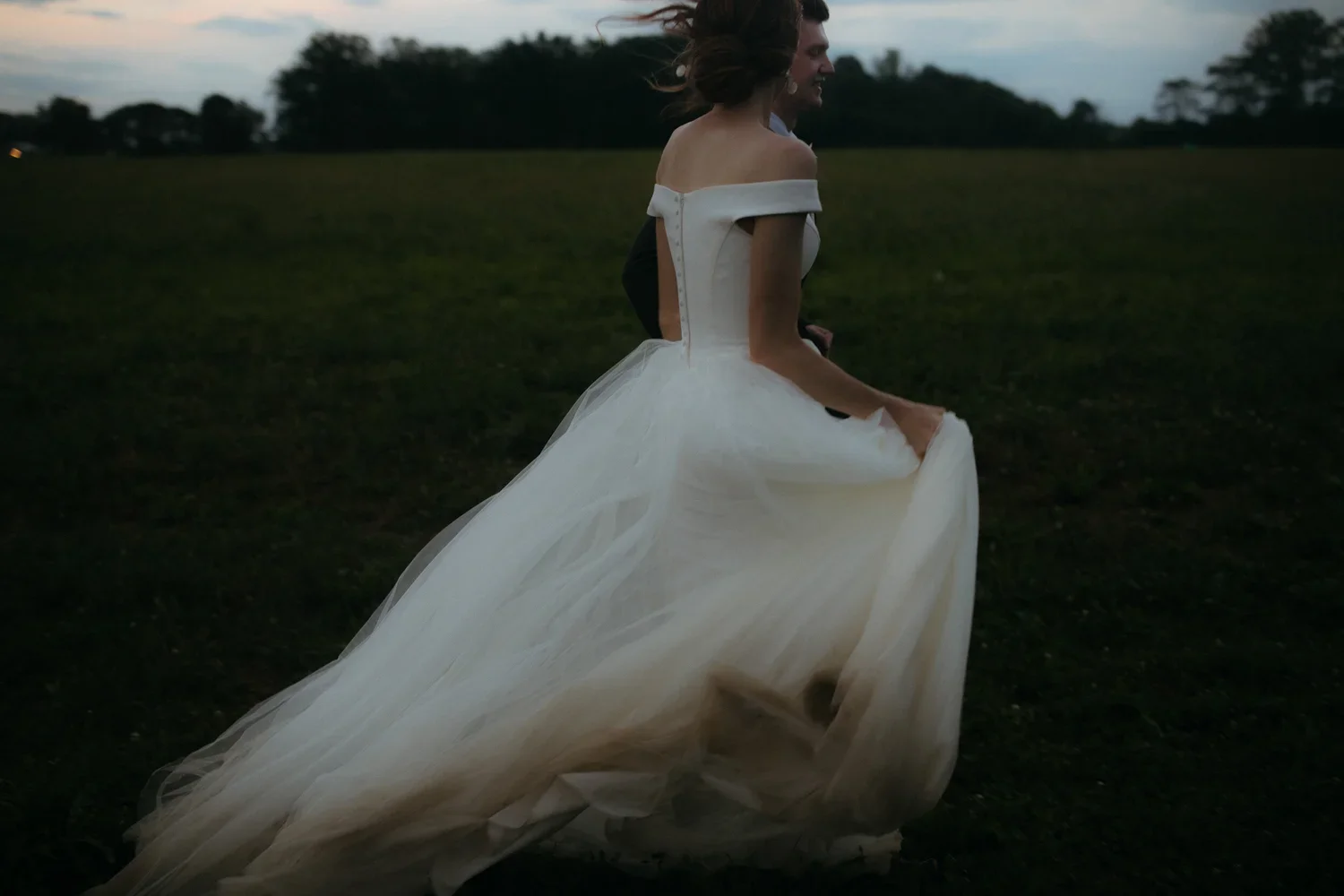 Bride running through an open field at sunset on her wedding day near Dayton, Ohio