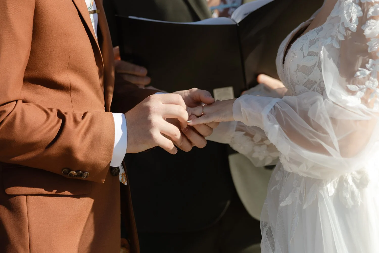Close-up of wedding ring exchange during an outdoor ceremony at Ivory Meadows
