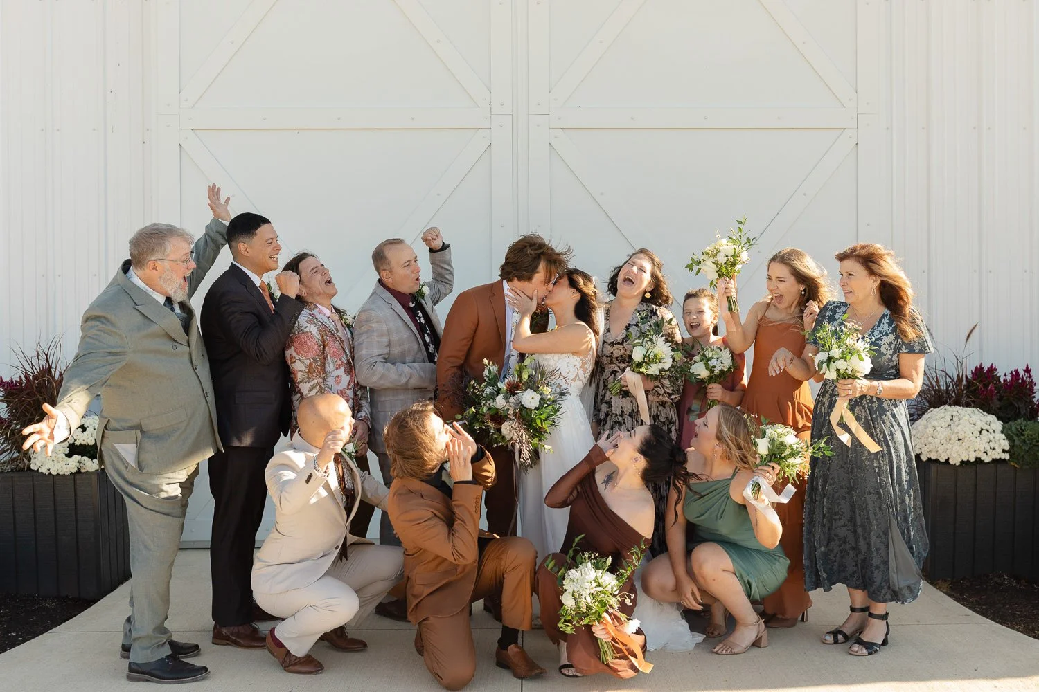 Wedding party celebrating with the bride and groom after the ceremony at Ivory Meadows in Dayton, Ohio, in front of the white barn doors