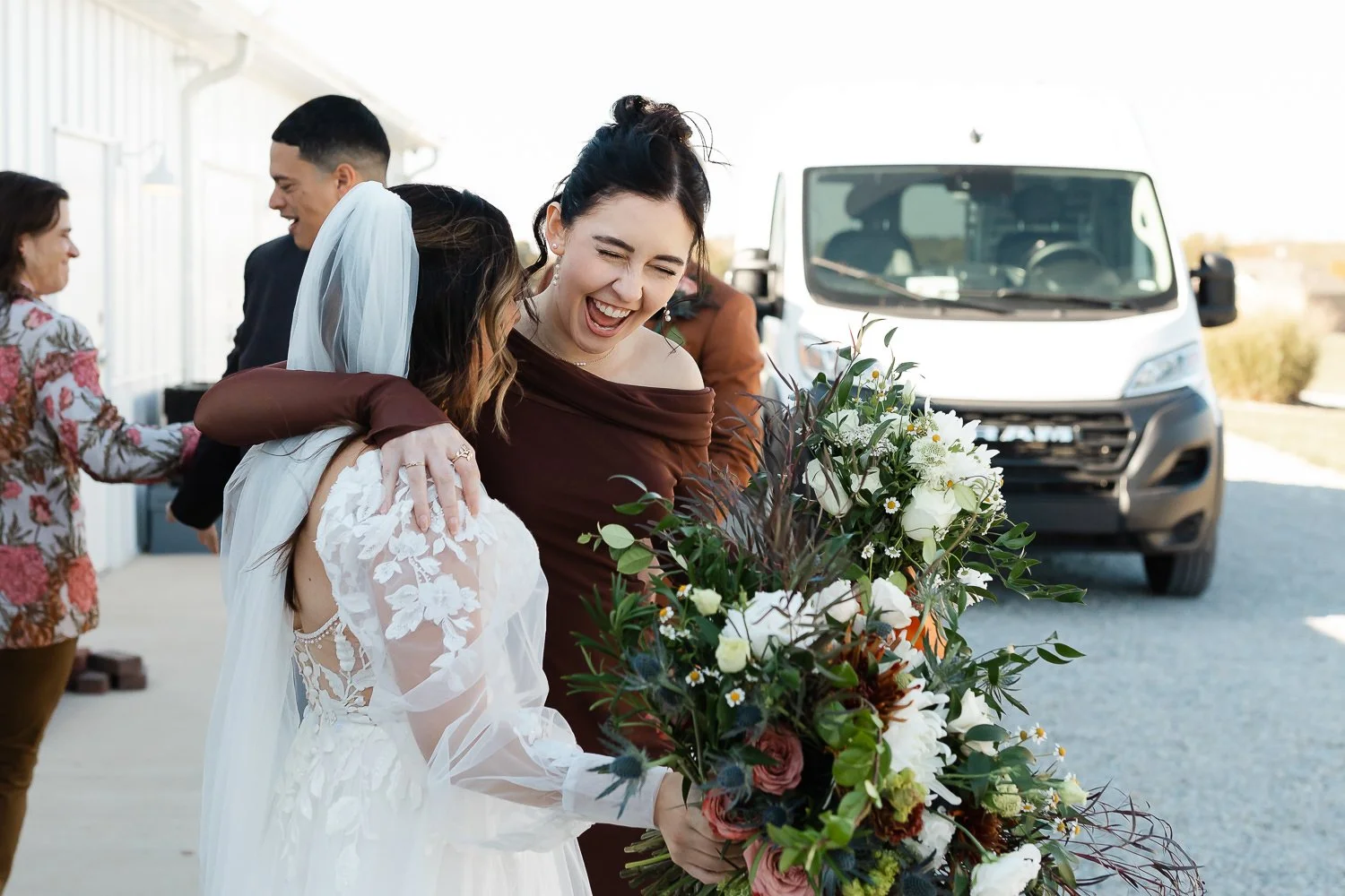 Bride hugging a bridesmaid after the ceremony at Ivory Meadows wedding venue in Dayton, Ohio, celebrating just after the recessional.