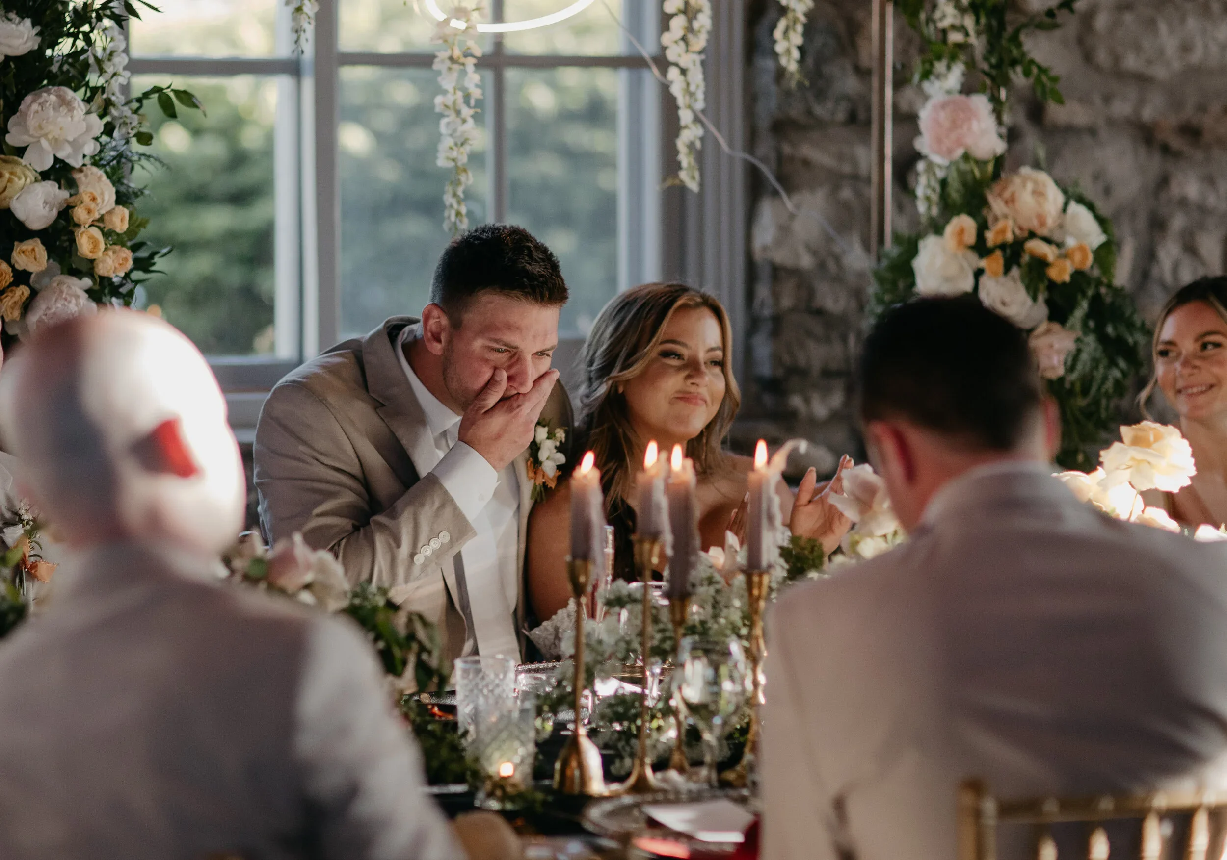Groom emotional during wedding toast at reception table, candid meaningful wedding moment