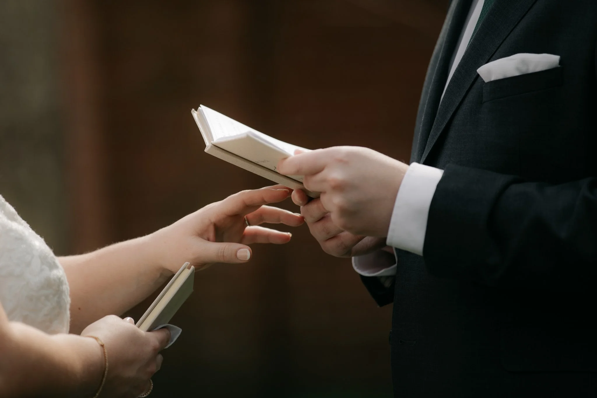 Bride and groom exchanging vow books during private vow reading