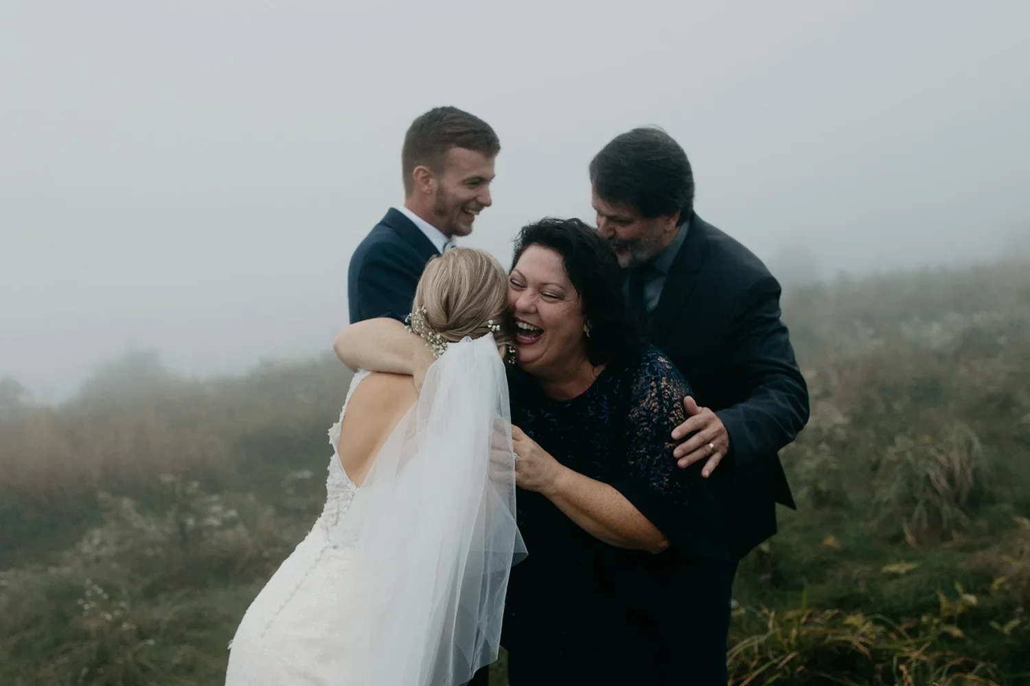 Bride hugging parents outdoors on wedding day, emotional candid wedding moment