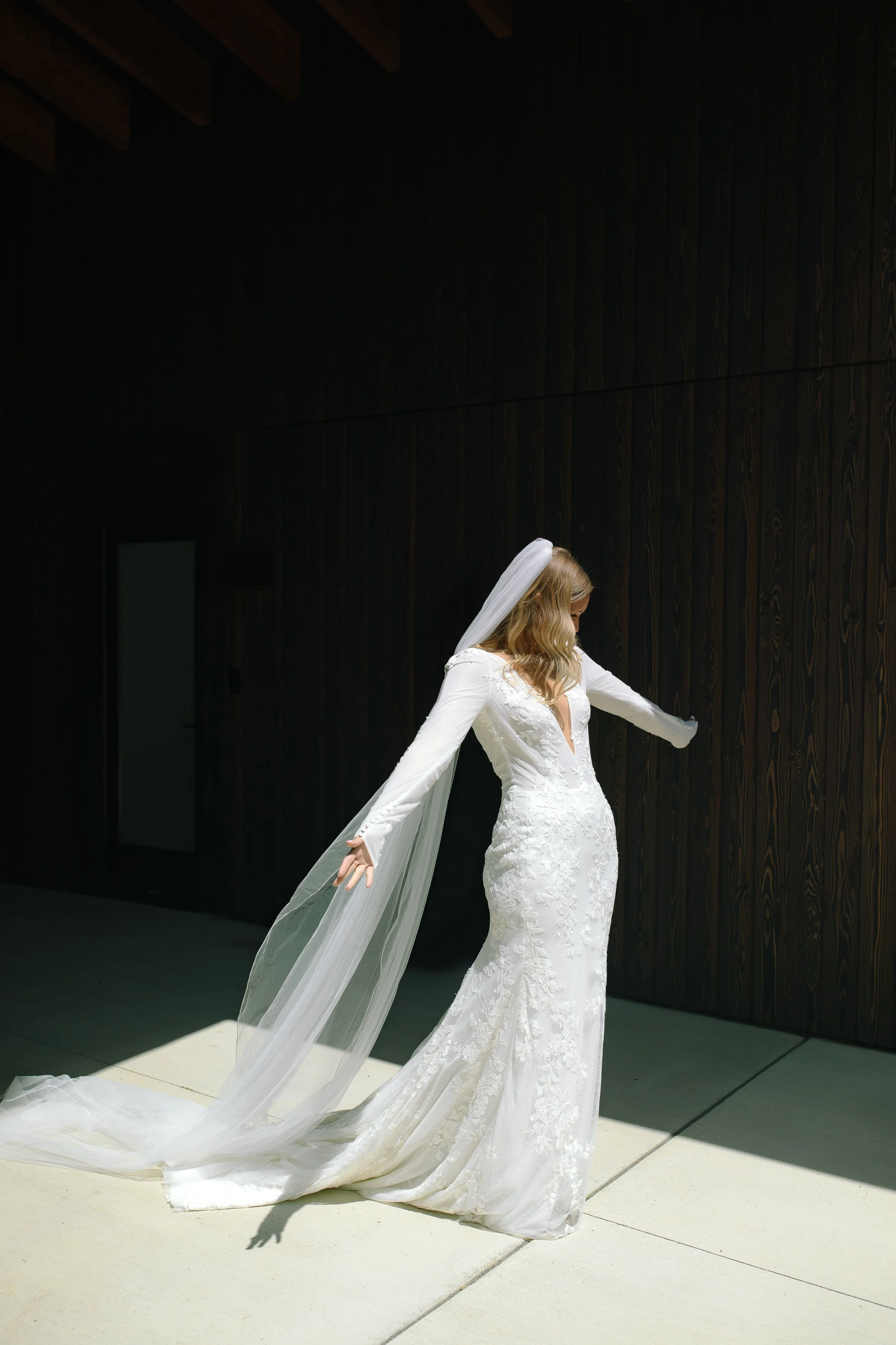 Bride stepping into bright spring sunlight before her first look with bridesmaids at Jorgensen Farm The Gardens in Columbus, Ohio.