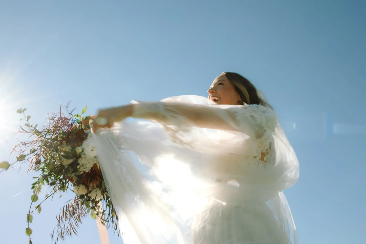Bride smiling as her veil moves in the wind during outdoor portraits at Ivory Meadows in Yellow Springs, Ohio.