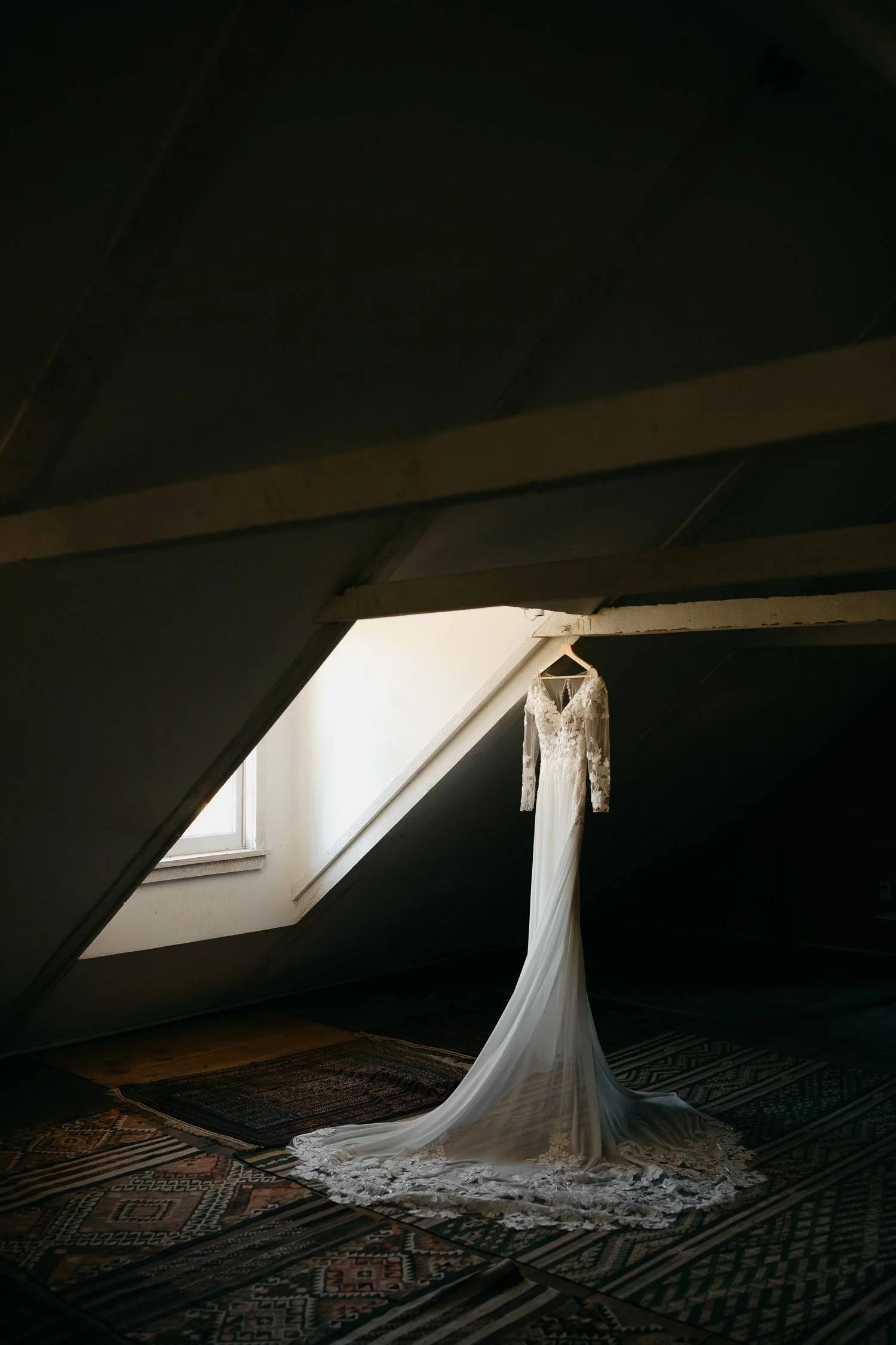Wedding dress hanging in the attic window of Windrift Hall during a Hudson Valley wedding morning