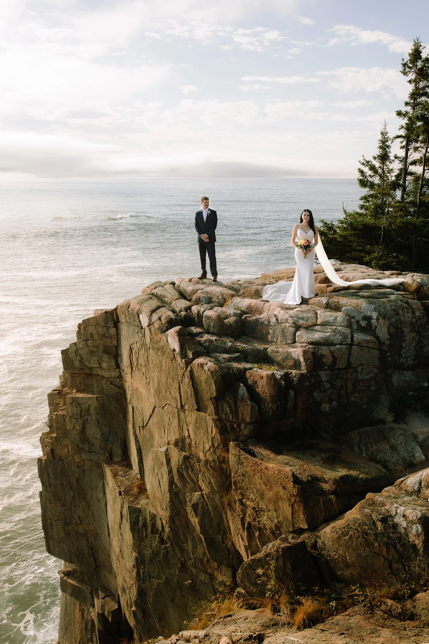 Couple standing on dramatic coastal cliffs during an early morning Acadia National Park elopement ceremony