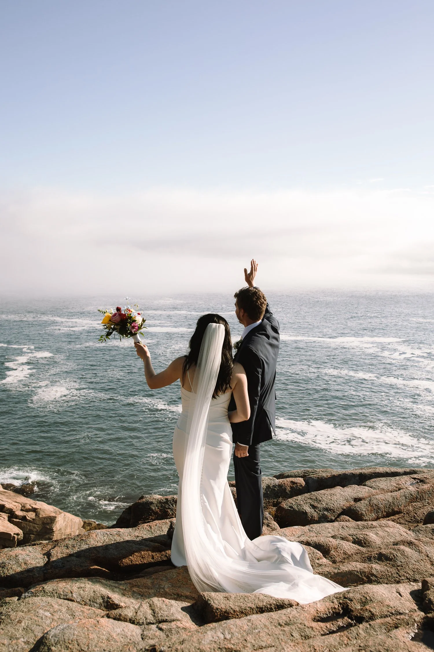 Couple facing the Atlantic Ocean during their Acadia National Park elopement ceremony on coastal cliffs