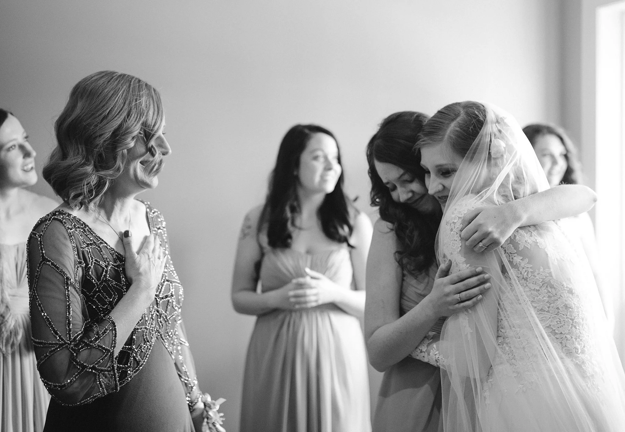 Bride hugging bridesmaid while getting ready, emotional candid wedding moment