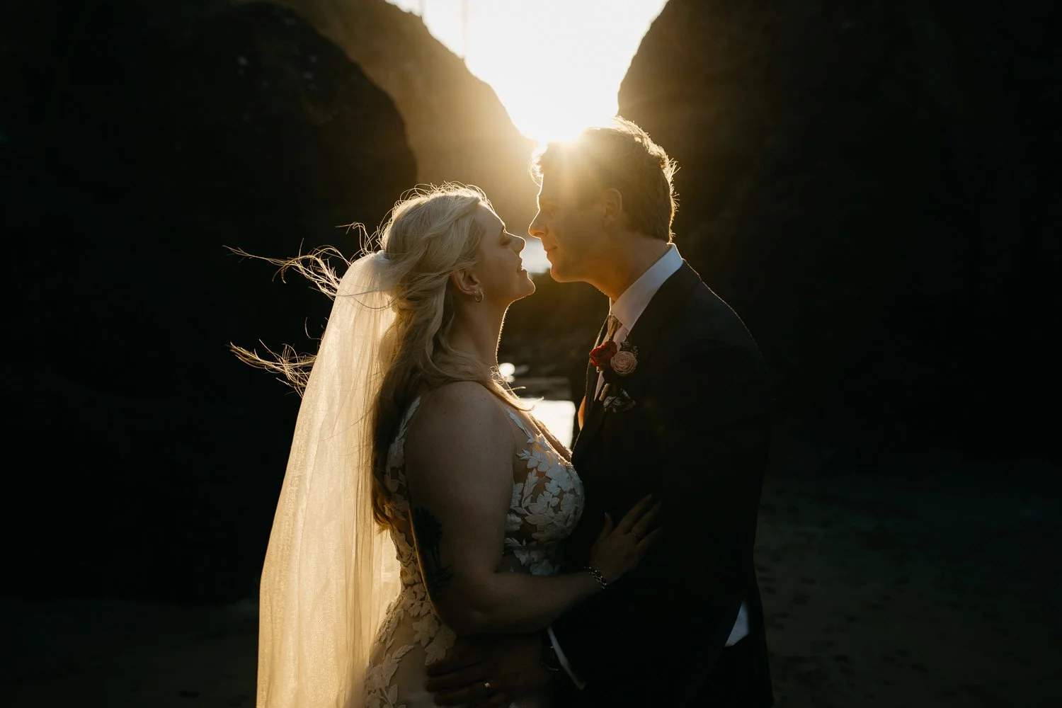 Silhouette portrait of bride and groom at sunset between dark rock formations