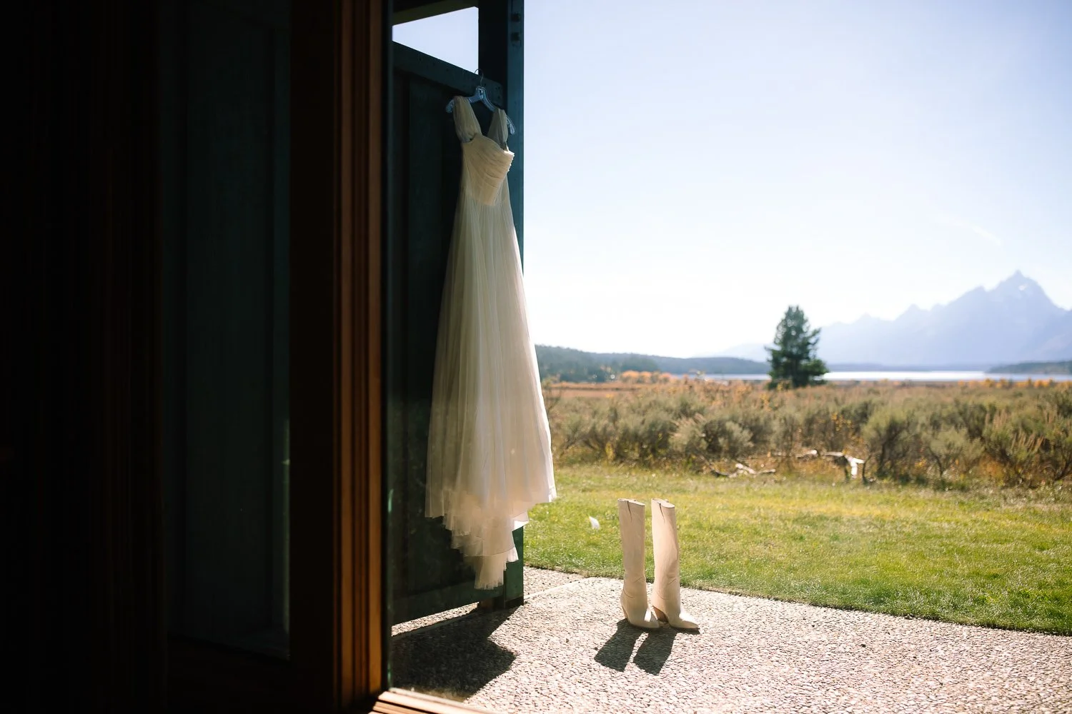 Wedding dress hanging in a doorway with Grand Teton mountain views in the distance