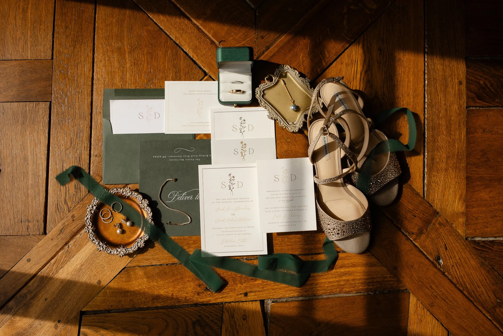 Wedding invitation suite, shoes, and details styled on wood floors at Peterloon Estate
