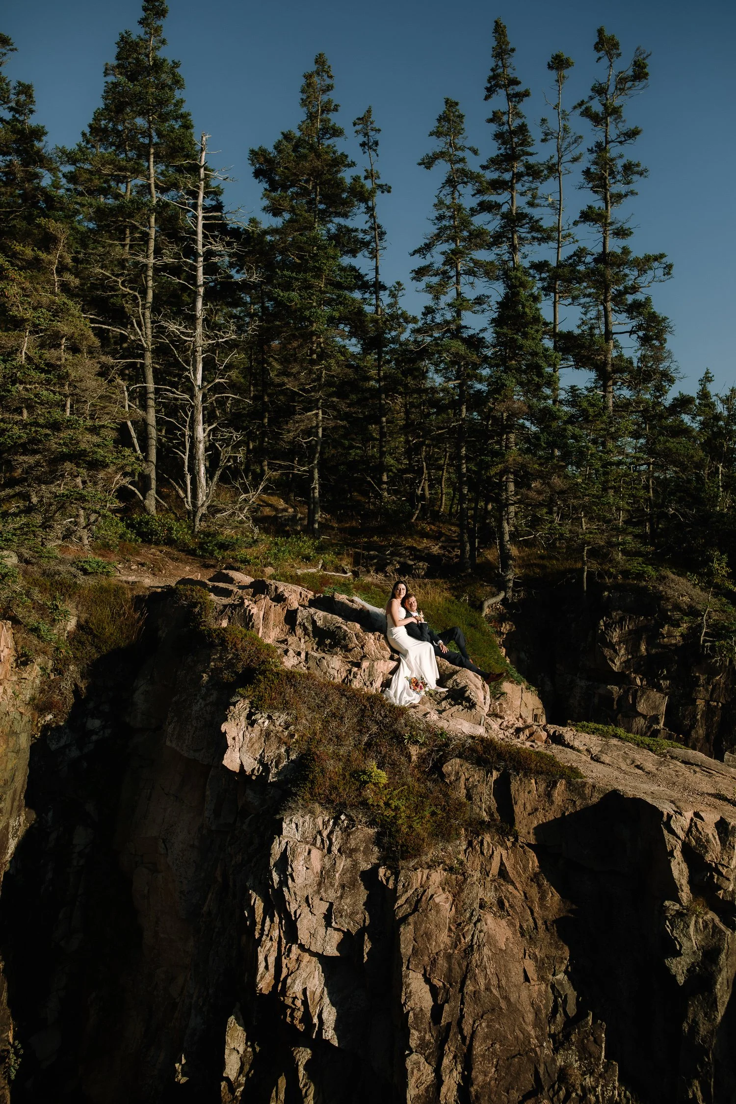 Bride and groom sitting quietly on exposed cliffs during an intimate Acadia National Park elopement at sunset