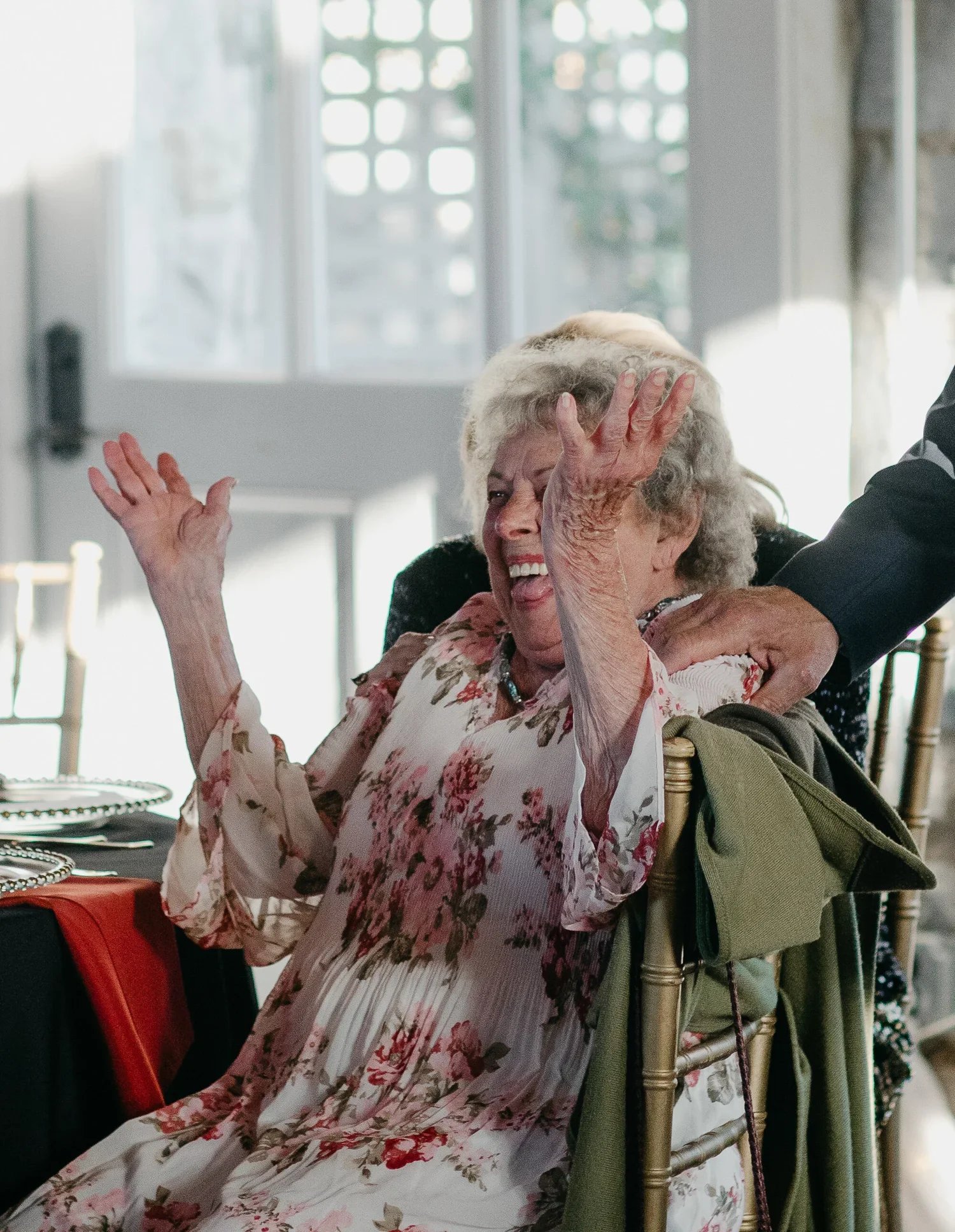 Emotional candid wedding photo of grandmother laughing during reception