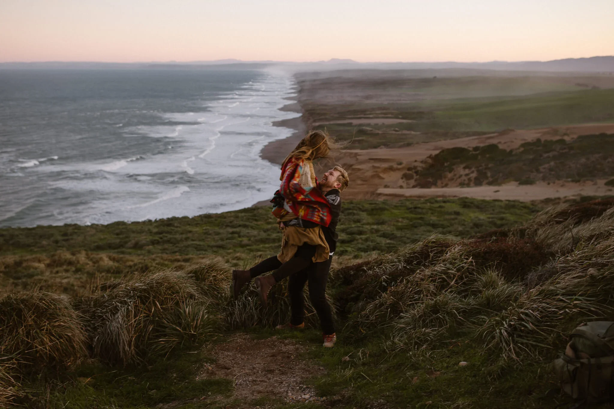 Playful couple portrait at sunset on the cliffs of Point Reyes National Seashore