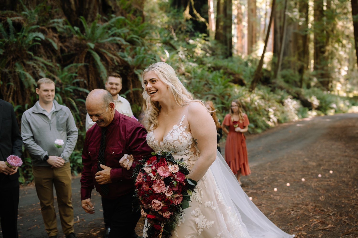 Bride walking down candle-lit forest aisle with her father in Prairie Creek Redwoods