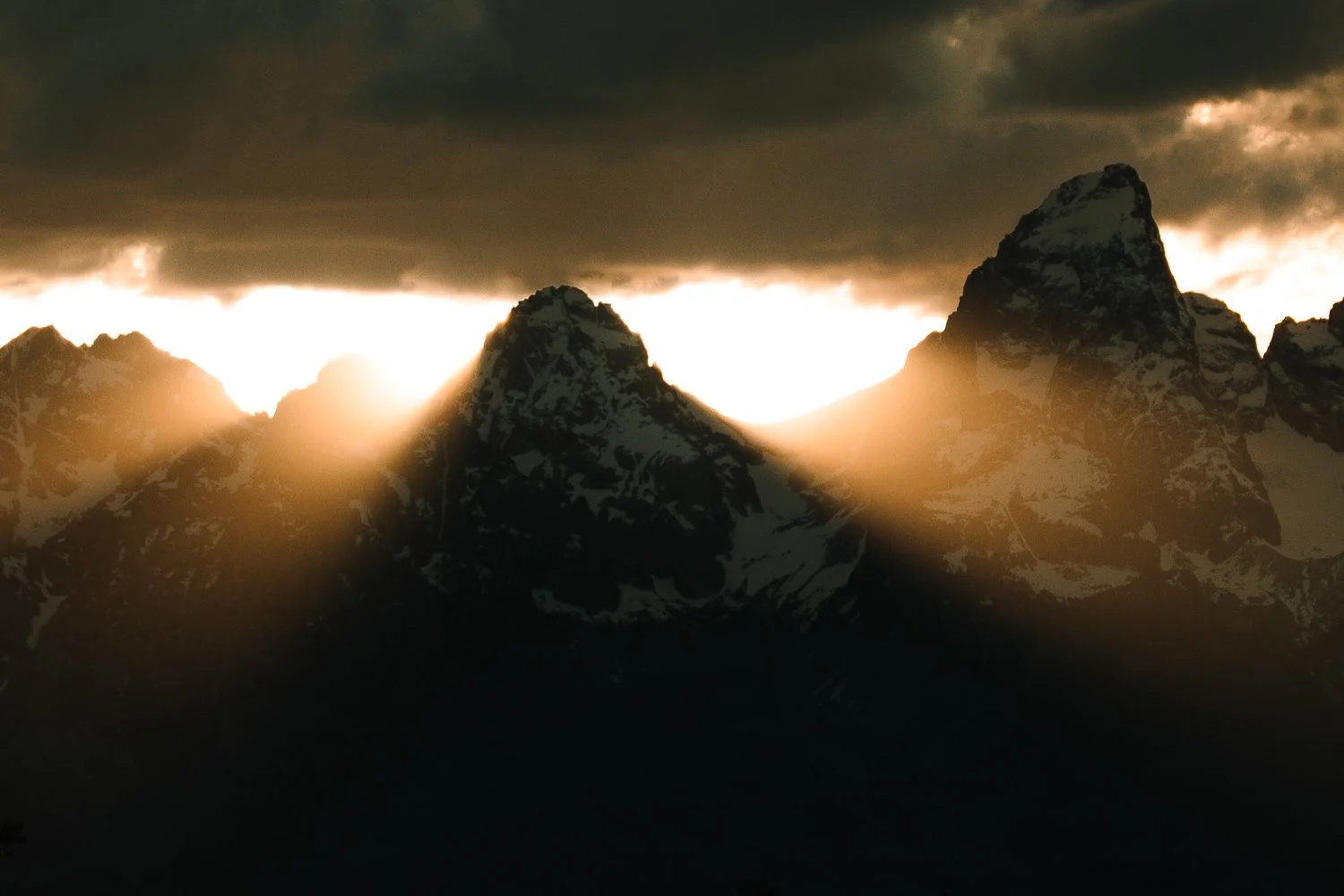 Golden sunset light breaking through storm clouds over the Teton Range near Jackson Hole, Wyoming