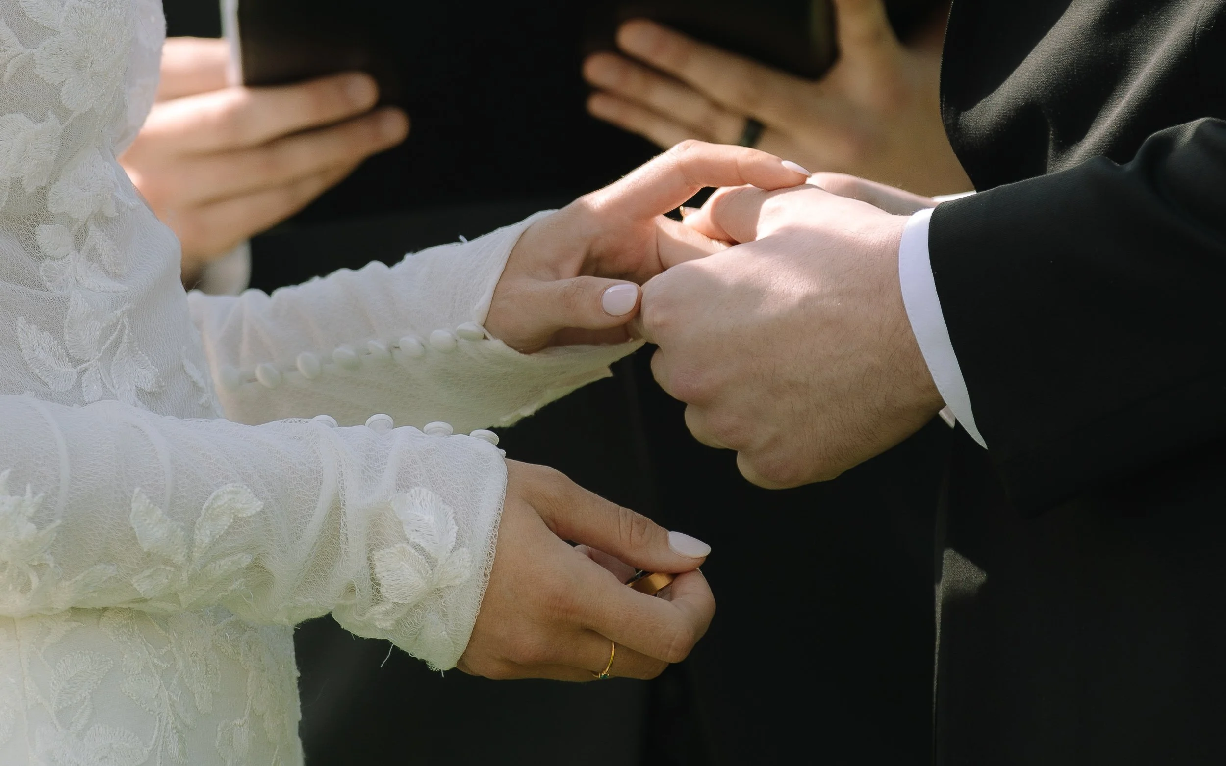 Close-up of the bride and groom exchanging rings during their outdoor ceremony at Jorgensen Farm The Gardens.