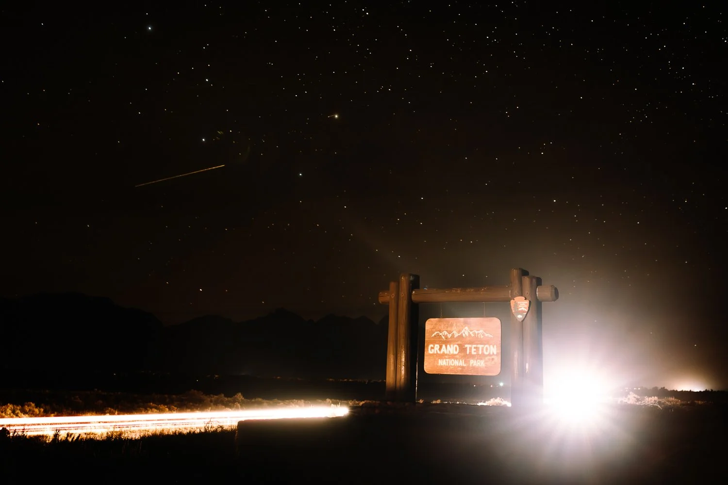 Grand Teton National Park entrance sign beneath a star-filled night sky