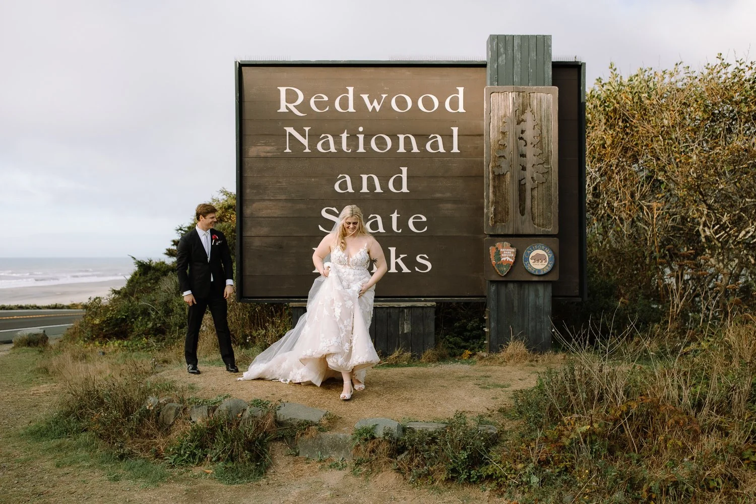 Couple standing near the Redwood National and State Parks entrance sign on their elopement day