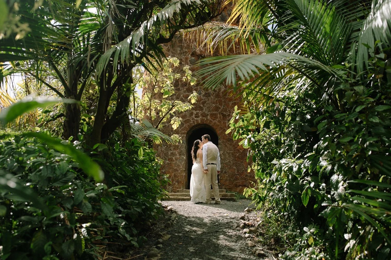 Eloping couple sharing a kiss beneath a jungle archway in El Yunque National Forest