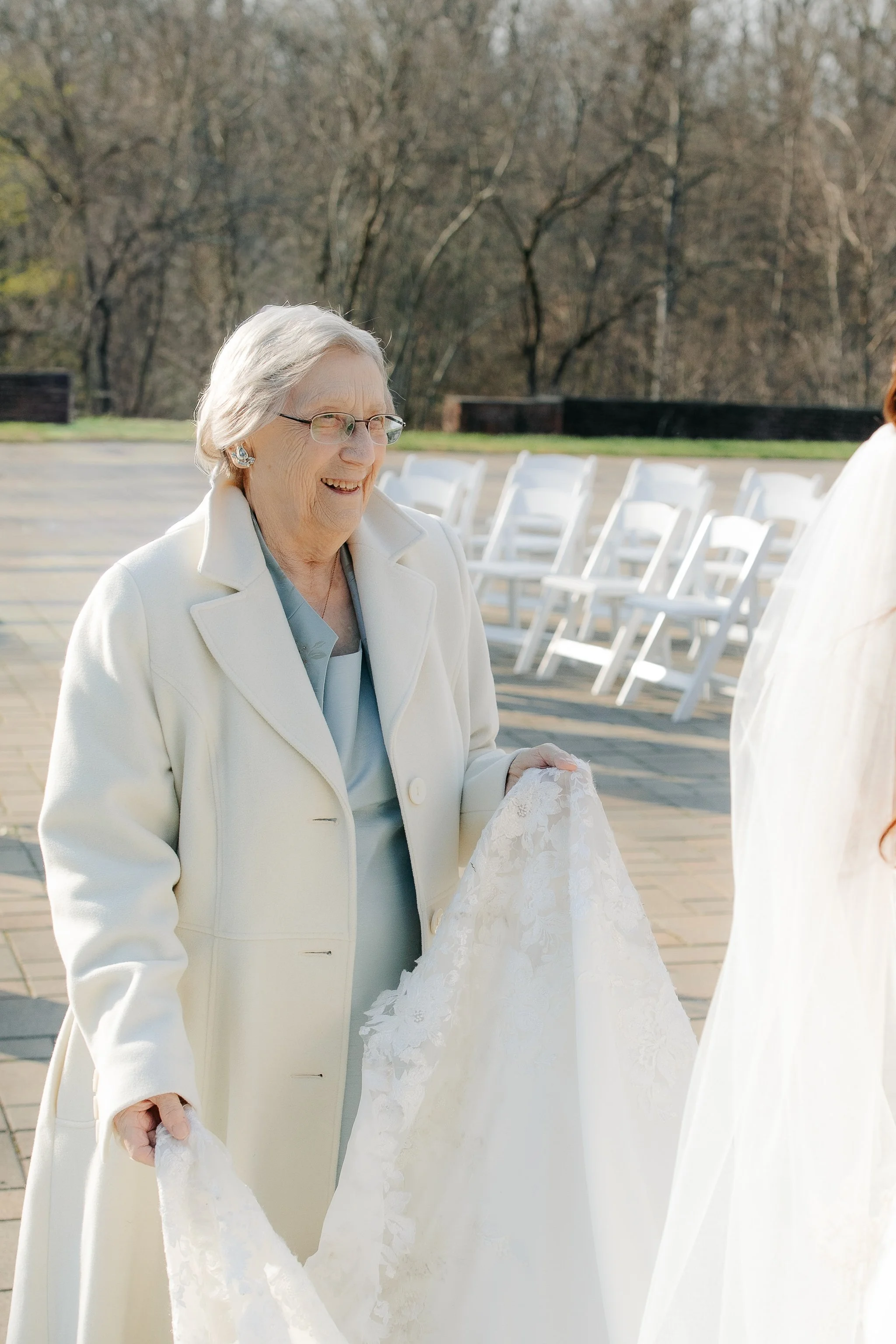 Grandmother smiling while holding bride’s train after ceremony