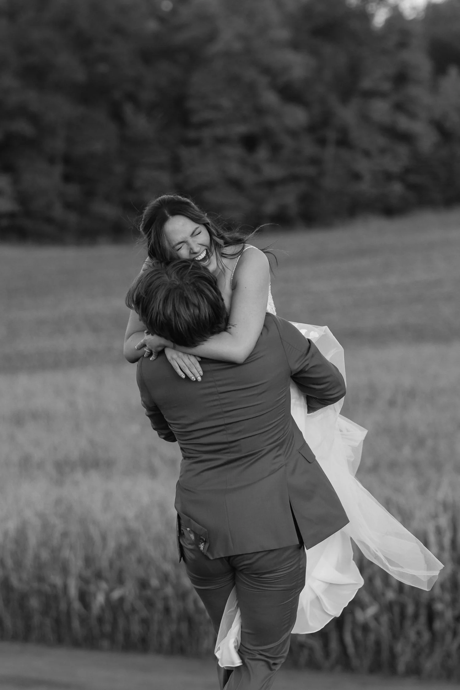 Bride laughing as the groom lifts her during evening portraits at Ivory Meadows in Dayton, Ohio.