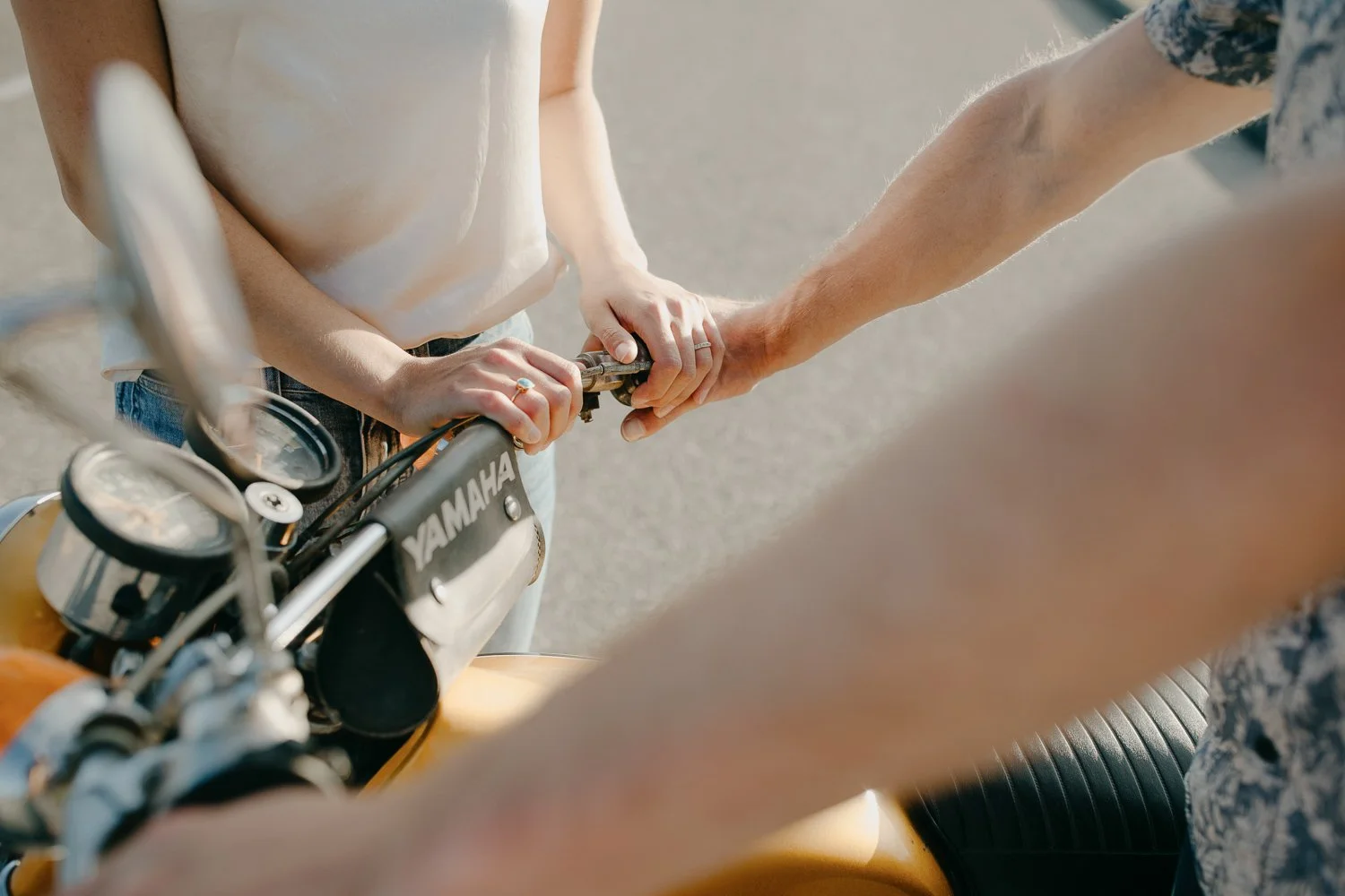 Close up of couple’s hands on a vintage motorcycle handlebars during engagement photos