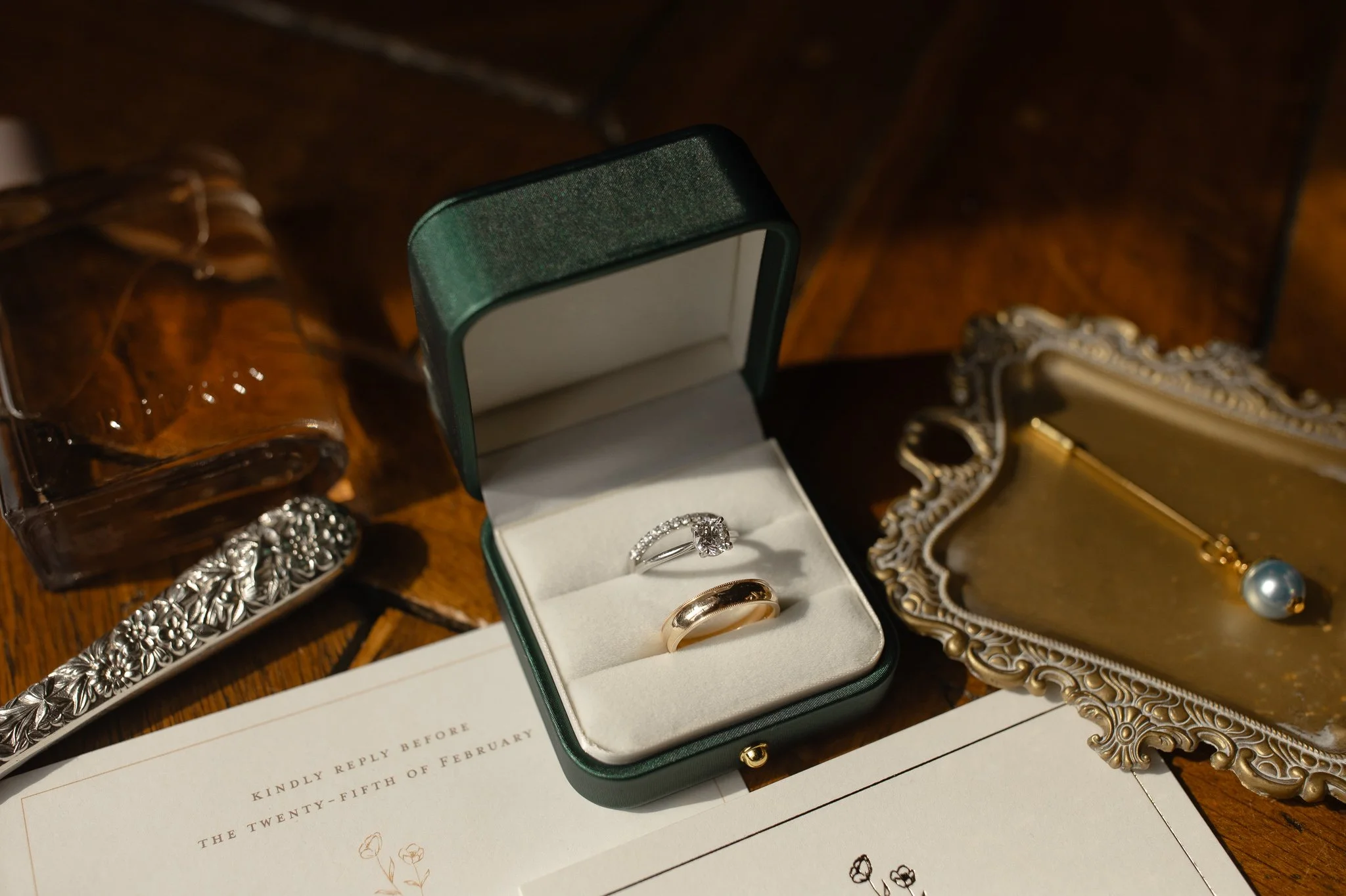 Wedding rings in green box on antique tray with invitation details