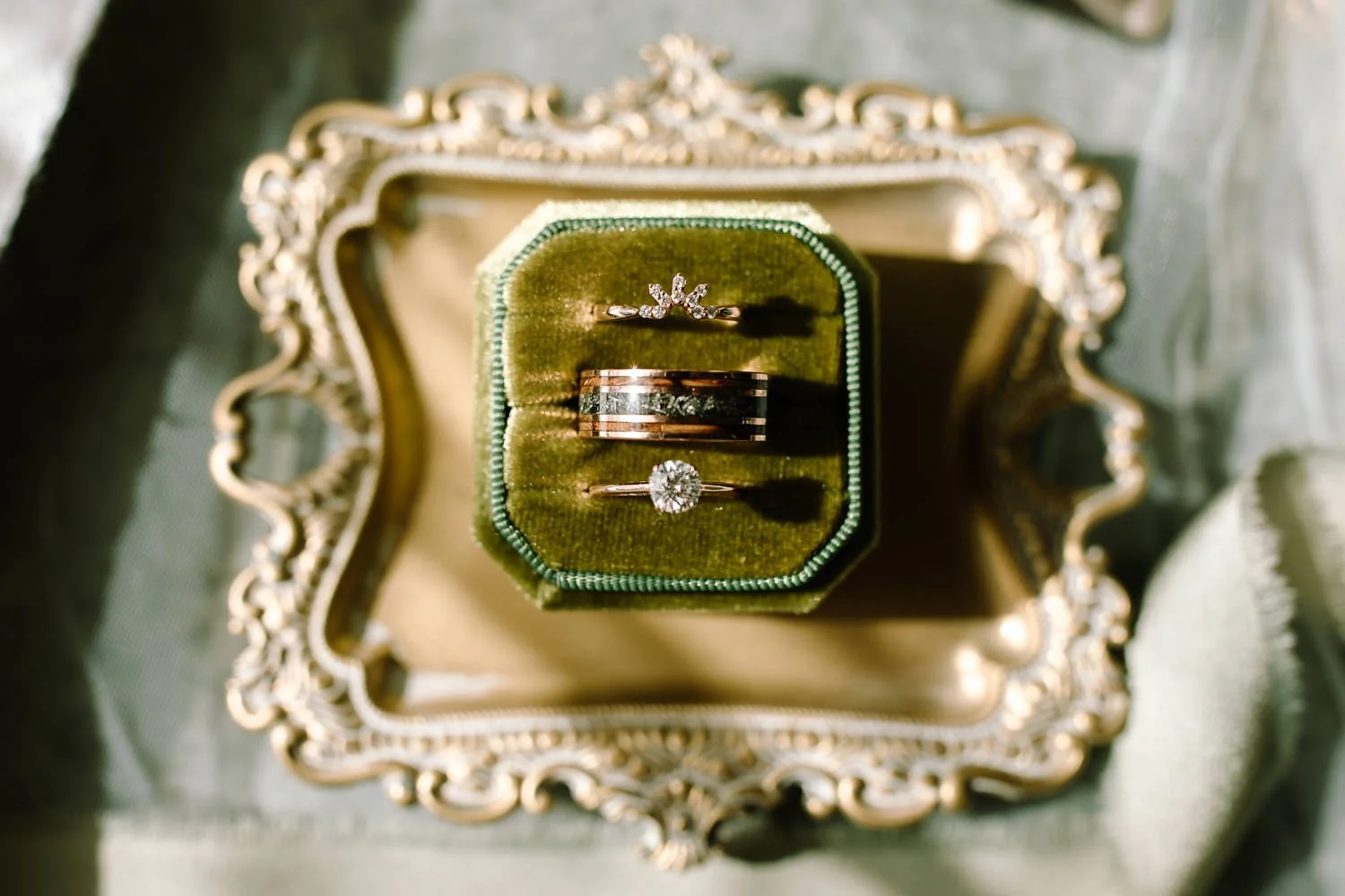 Wedding rings displayed in a green velvet ring box during an Ivory Meadows wedding in Yellow Springs, Ohio, photographed in soft natural light.
