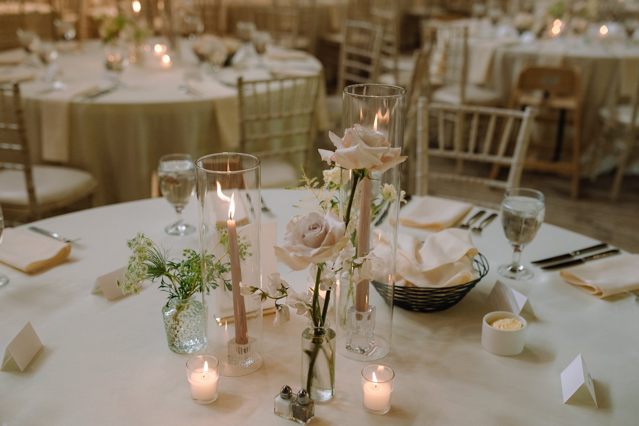 Reception table with candles, glassware, and spring florals inside the historic barn at Jorgensen Farms.
