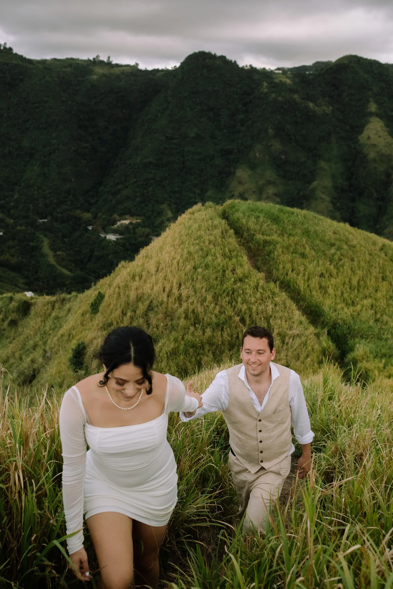 Couple hiking up a steep grassy trail at Cerro Mime during their elopement photo session