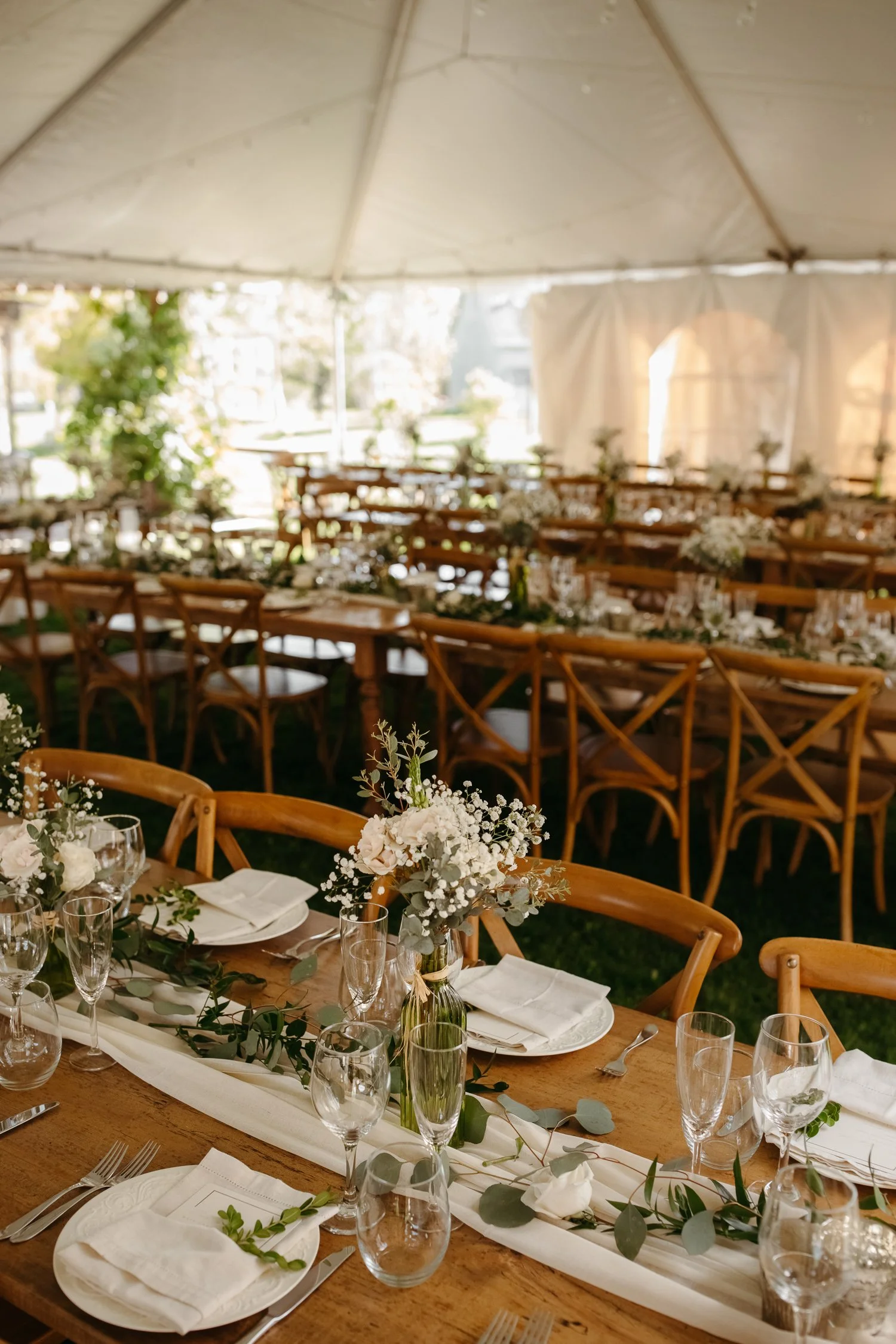 Reception tent decorated with farm tables, greenery, and string lights at a Catskills wedding