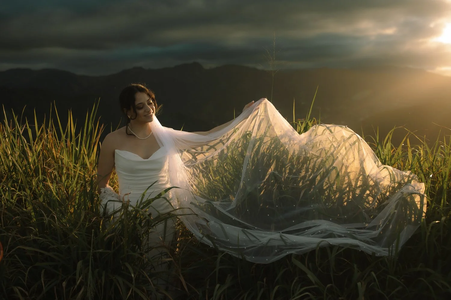 Bride standing in tall grass holding her veil during a Cerro Mime mountain elopement in Puerto Rico