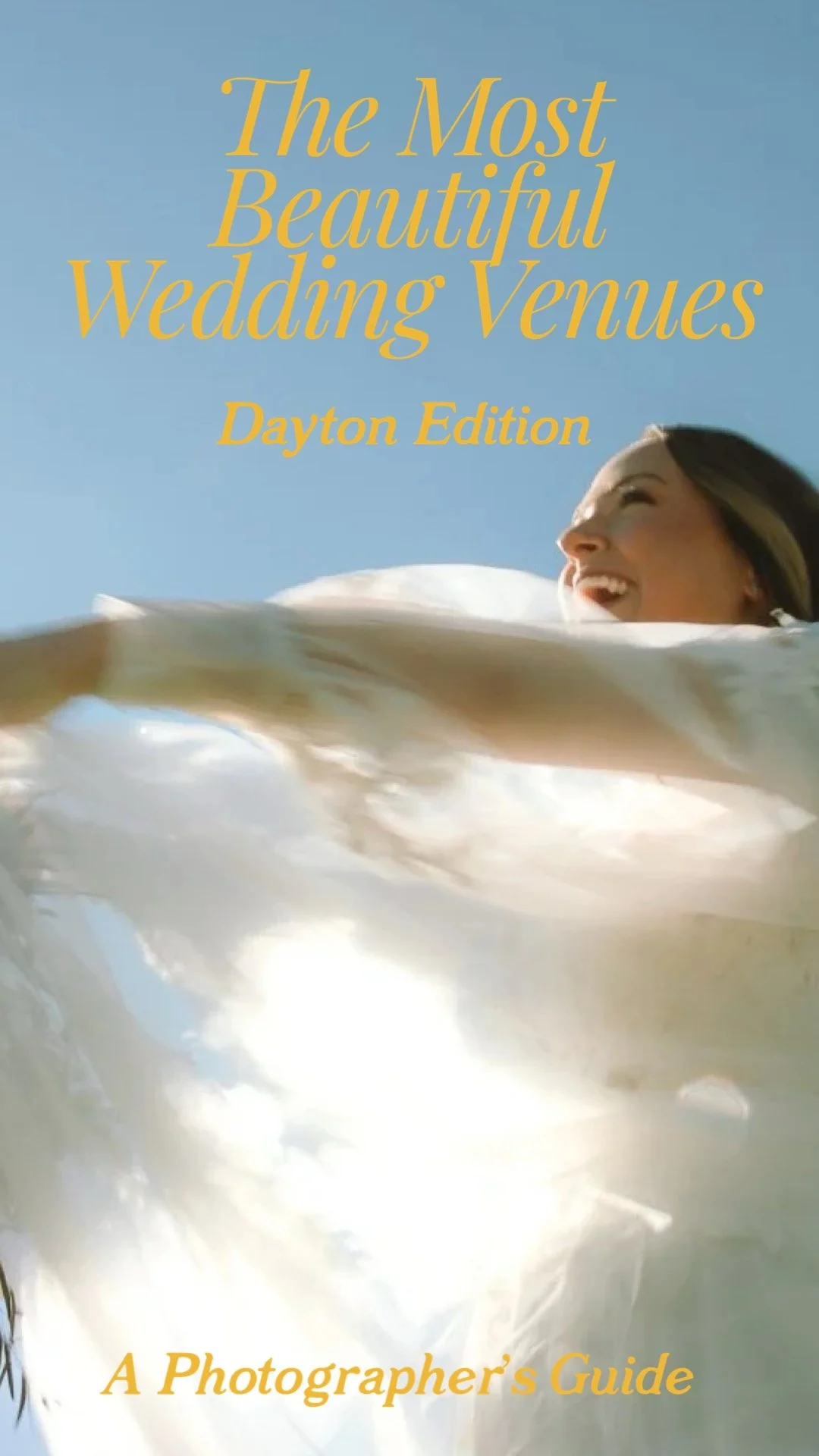 Bride spinning joyfully in flowing veil under blue sky, photographed at a beautiful wedding venue near Dayton Ohio.