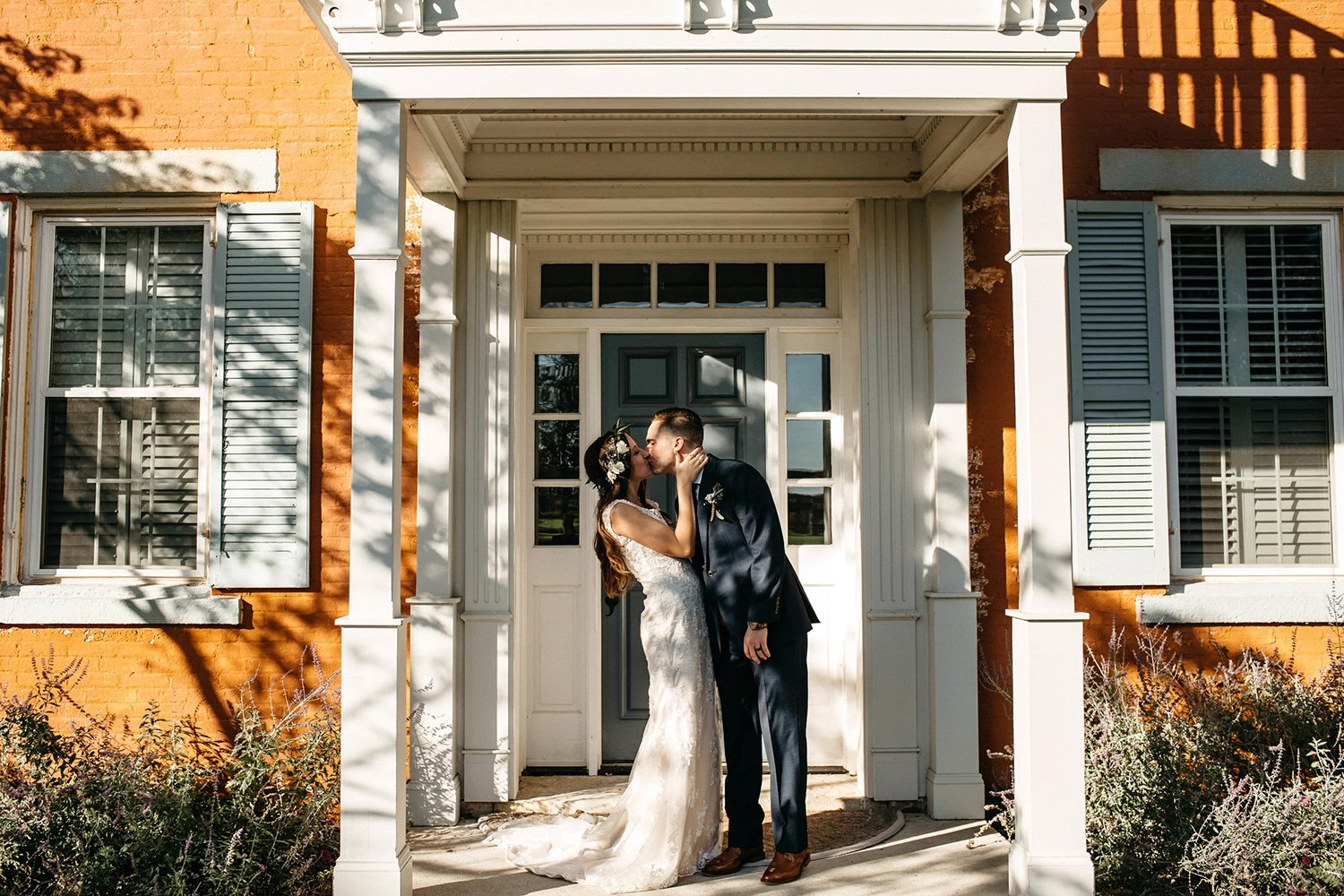 Bride and groom share a kiss in front of the historic brick building at The Willow Tree wedding venue near Dayton, Ohio.