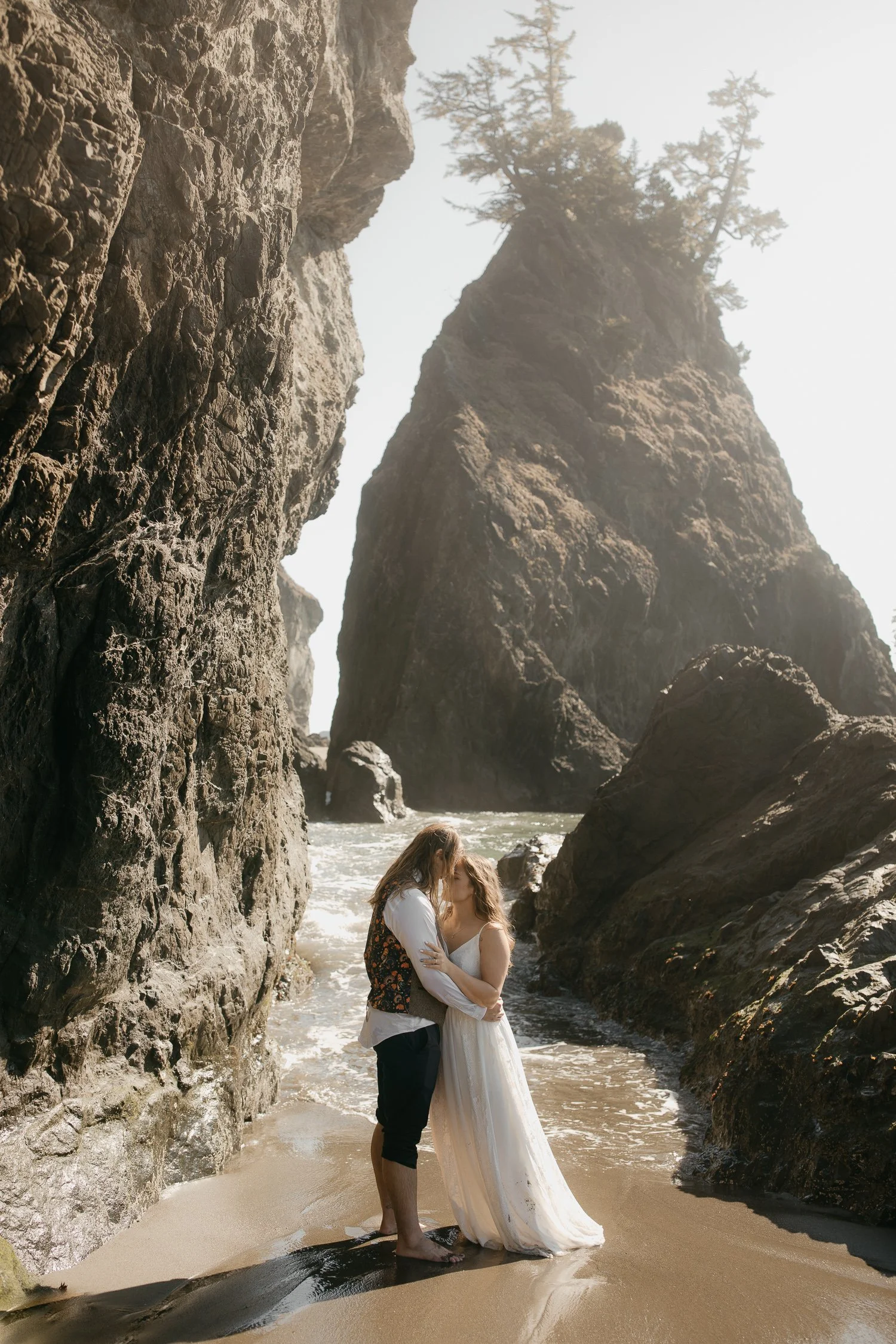 Couple embracing between towering sea stacks during a southern Oregon coast beach session