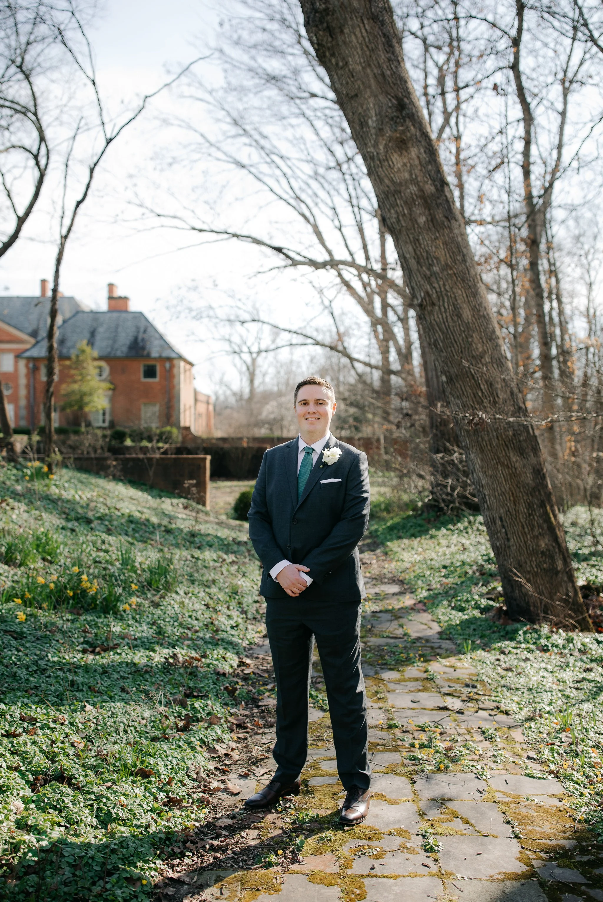 Groom standing for portrait in garden area at Peterloon Estate