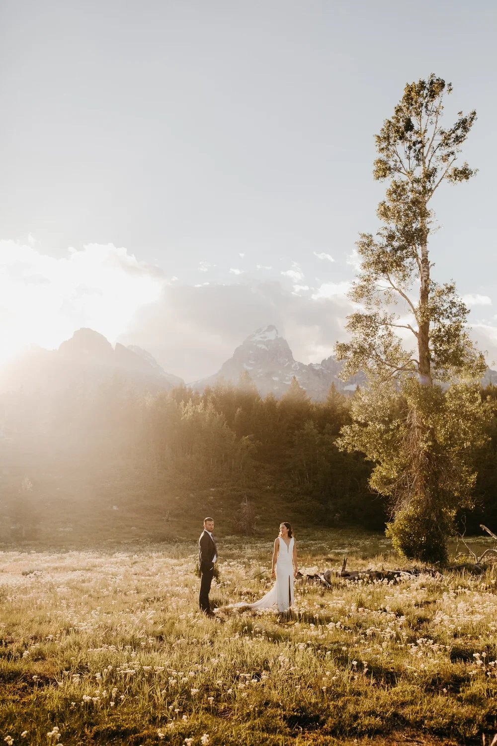 Couple standing together during a Wedding Tree elopement in Grand Teton National Park surrounded by soft evening light.