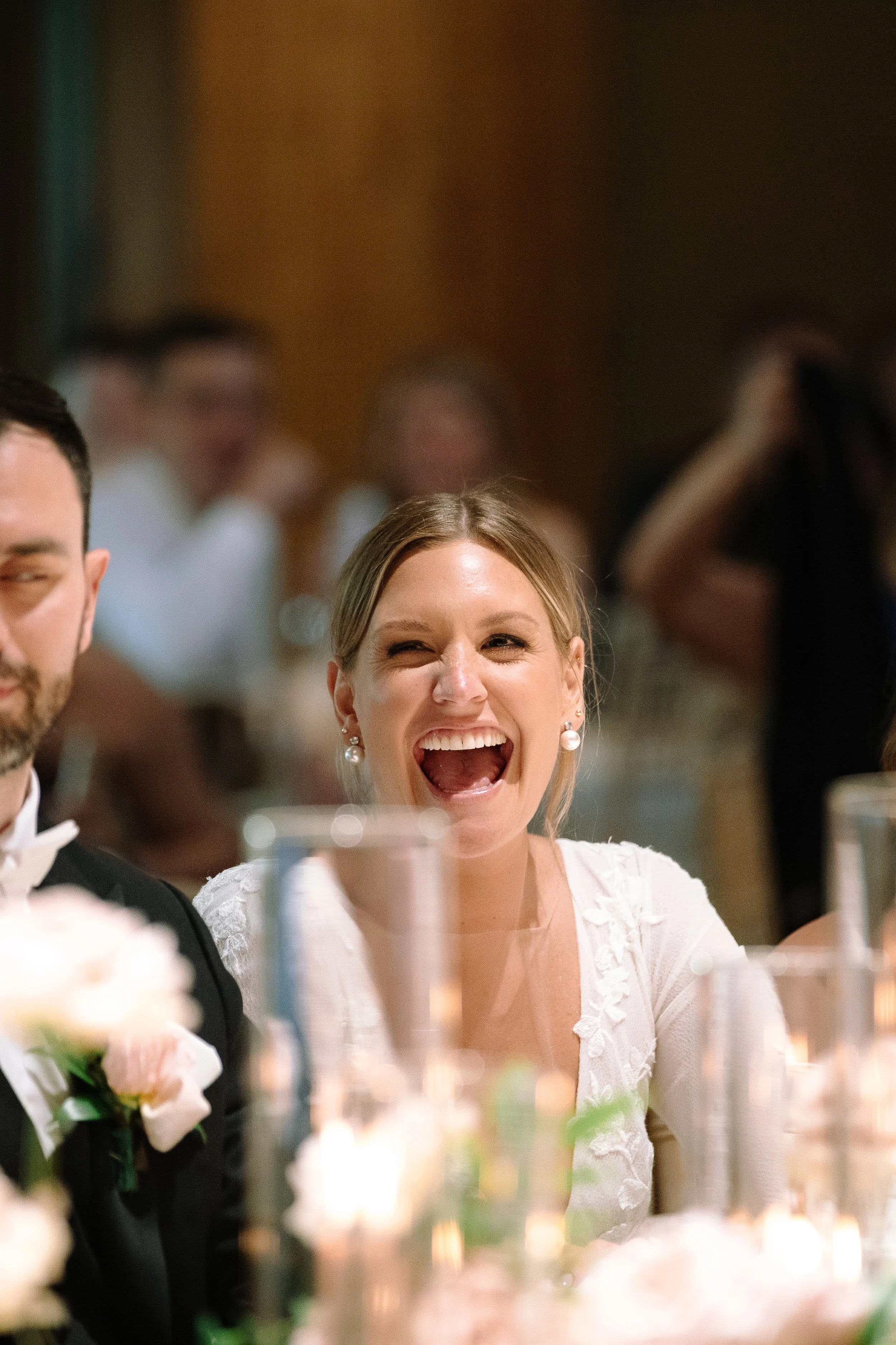 Bride laughing during a reception speech inside the historic barn at Jorgensen Farms in Columbus.