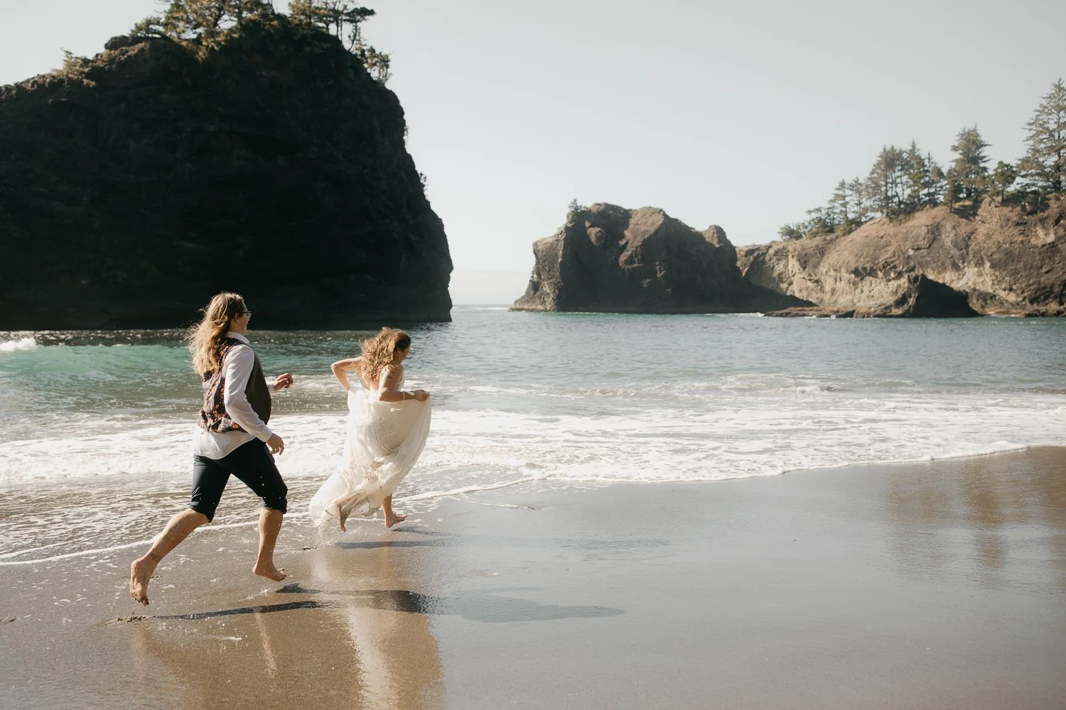 Couple running through ocean waves on the southern Oregon coast