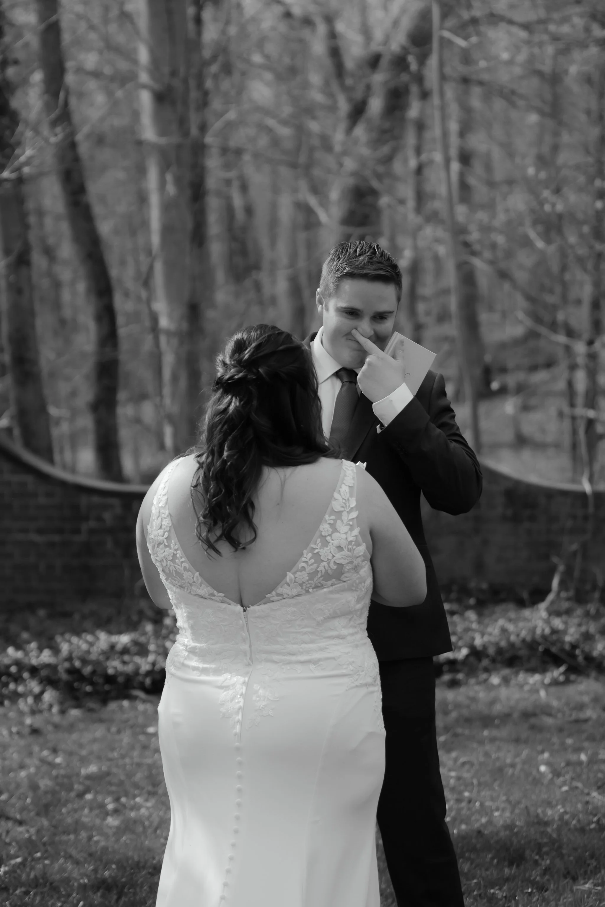 Groom wiping tears while reading vows during intimate outdoor wedding