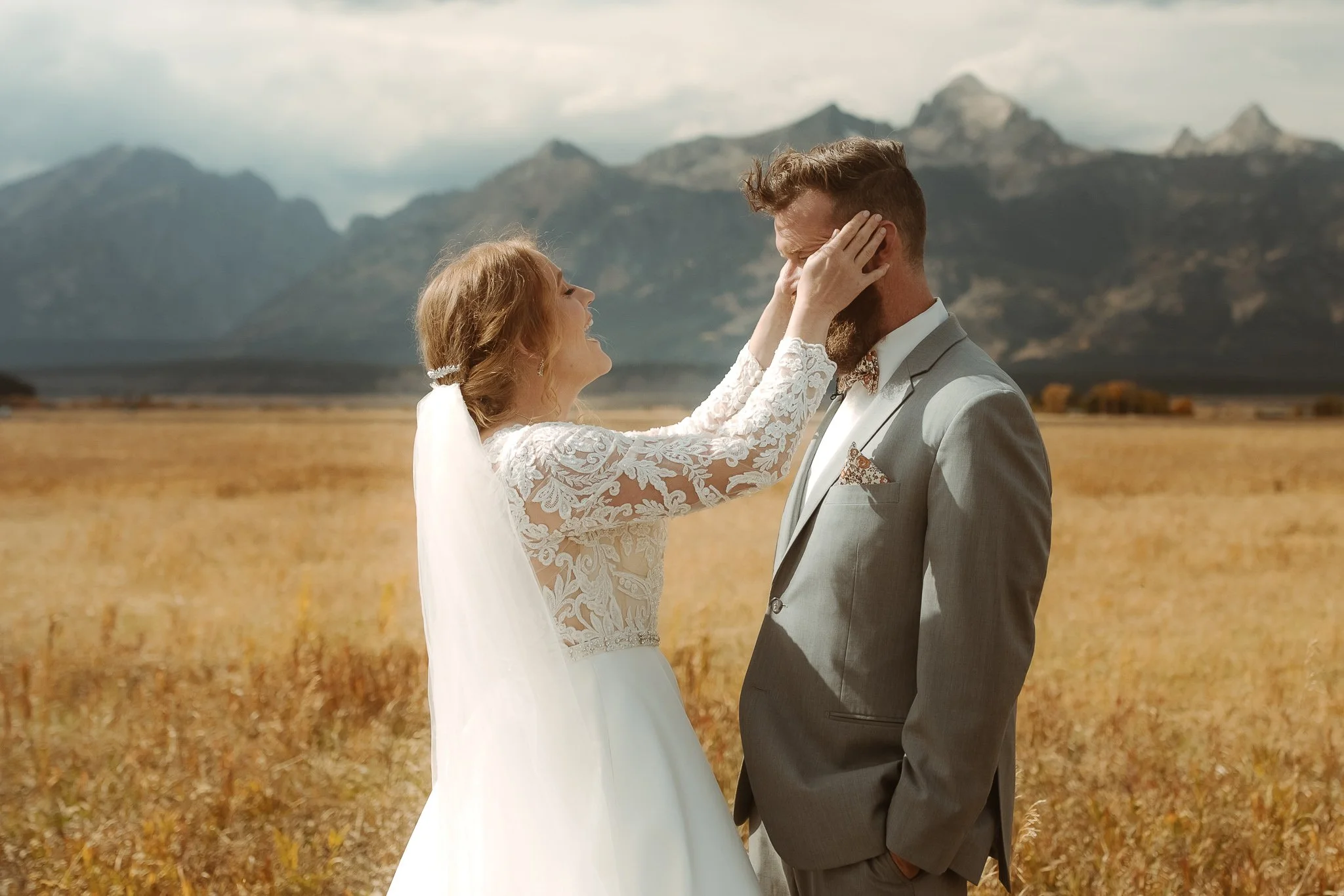 Bride holding groom’s face during an emotional moment with the Grand Teton mountains behind them